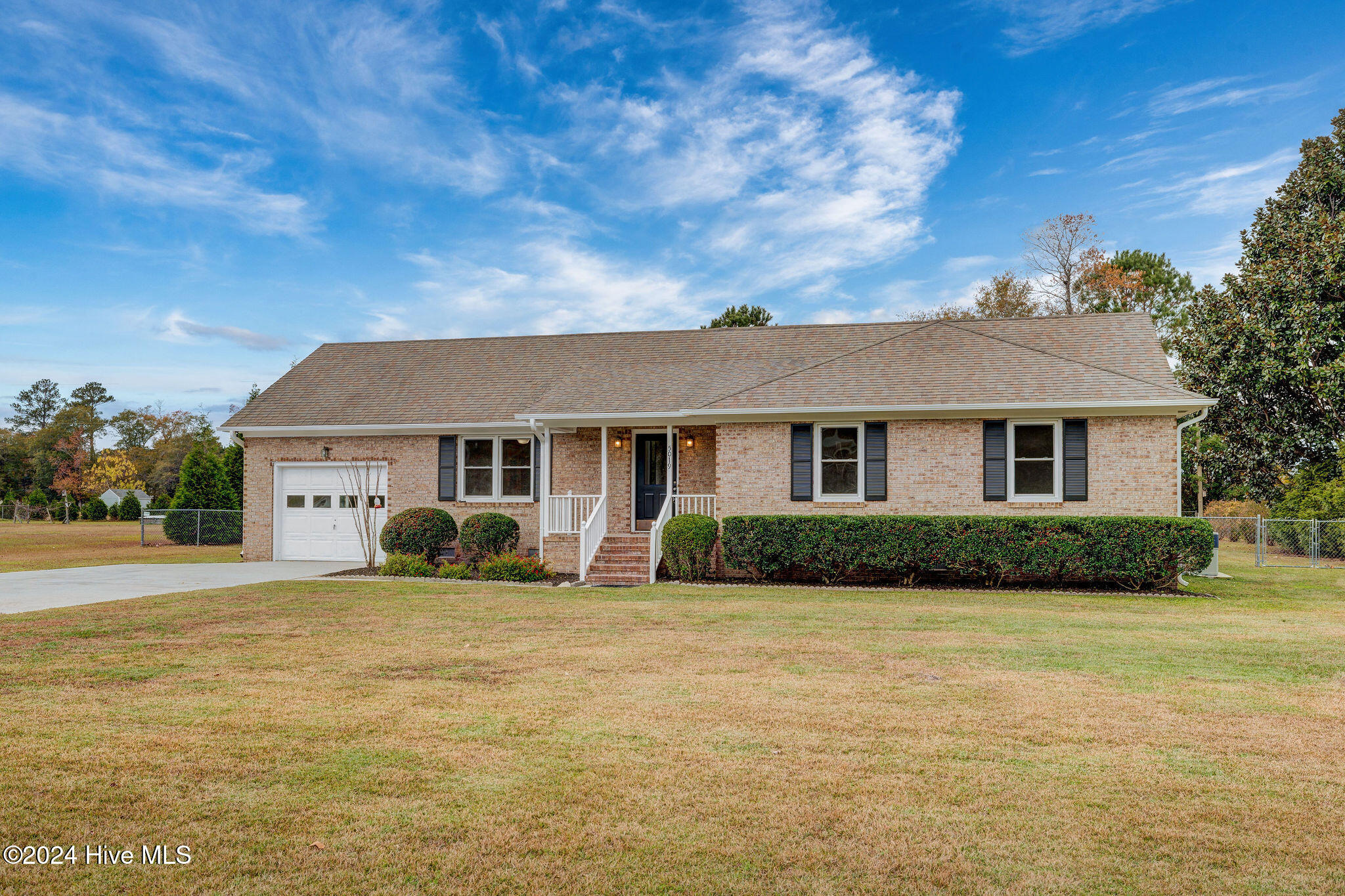 Brick ranch home with an attached garage, covered entry, and broad front lawn.