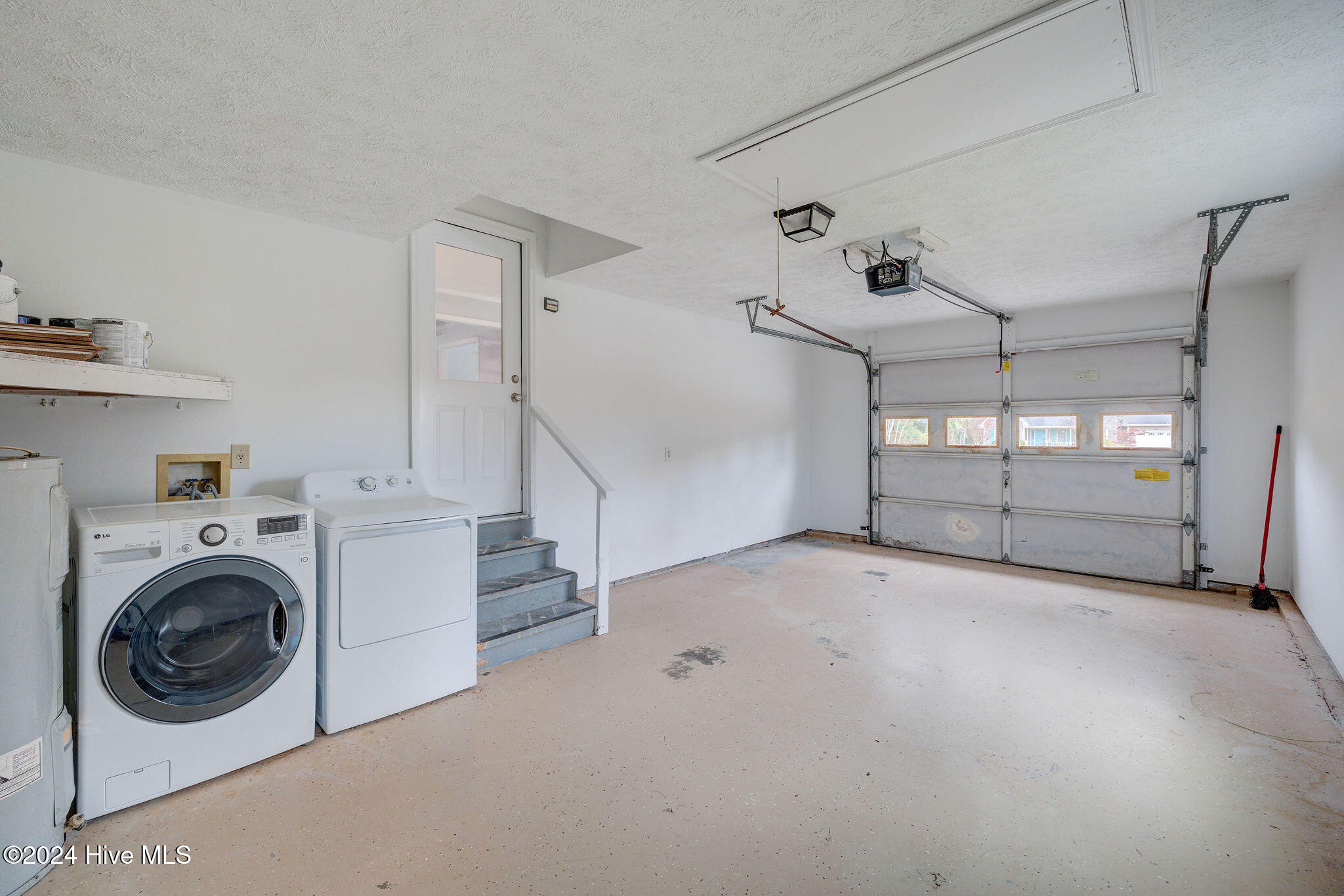 Garage with washer and dryer, steps to an interior door, and a windowed overhead door.