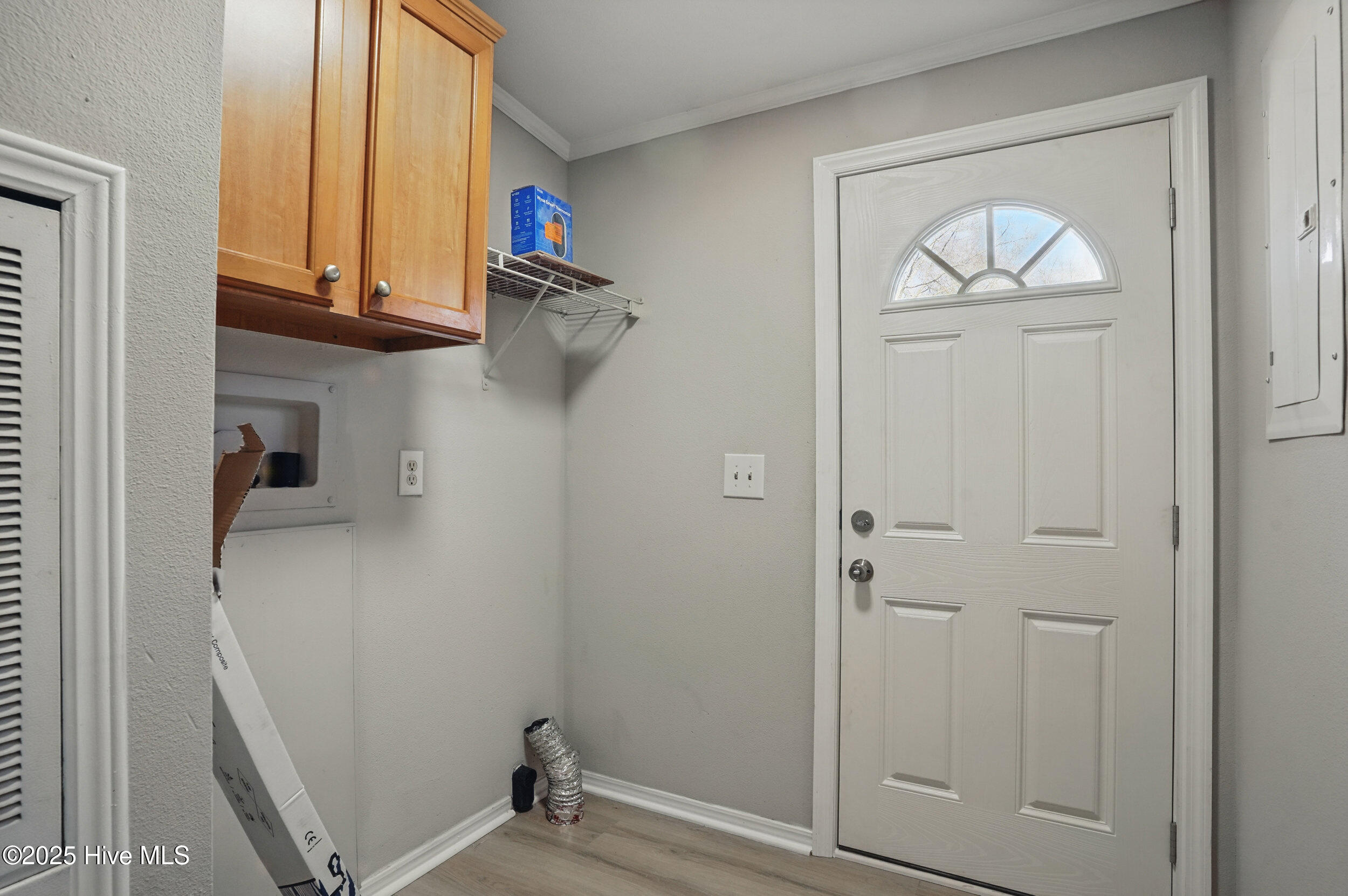 Entryway with a white front door, overhead wood cabinets, and exposed HVAC ducting.