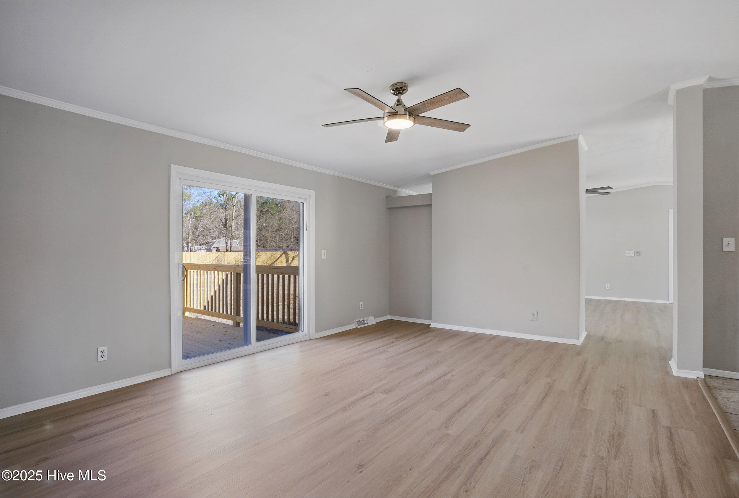 Unfurnished living room with light wood floors, a ceiling fan, and sliding glass doors to a deck.