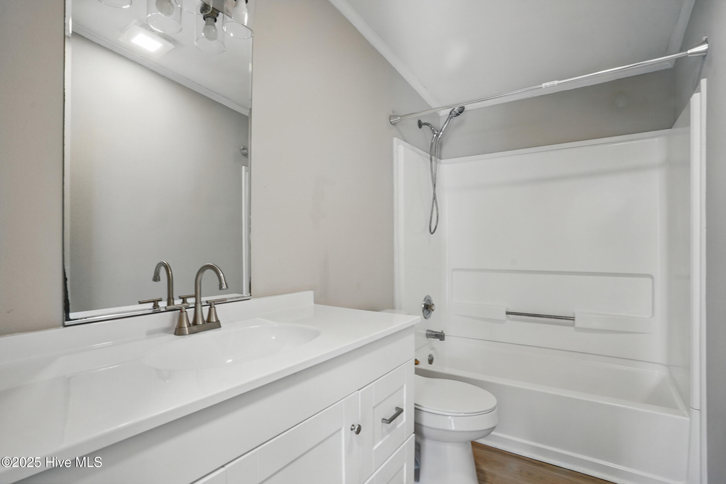 Bathroom with a white vanity, large mirror, and tub-shower combination.