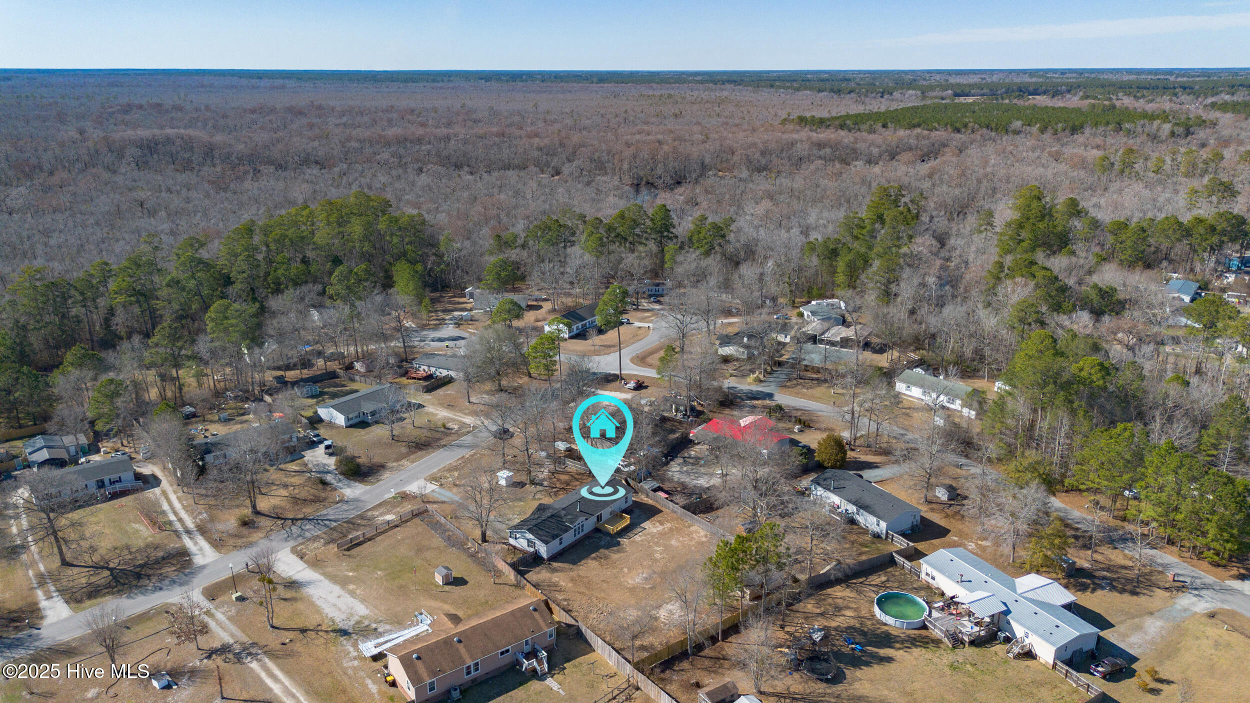 Aerial view of a home among wooded lots, identified by a turquoise map pin.