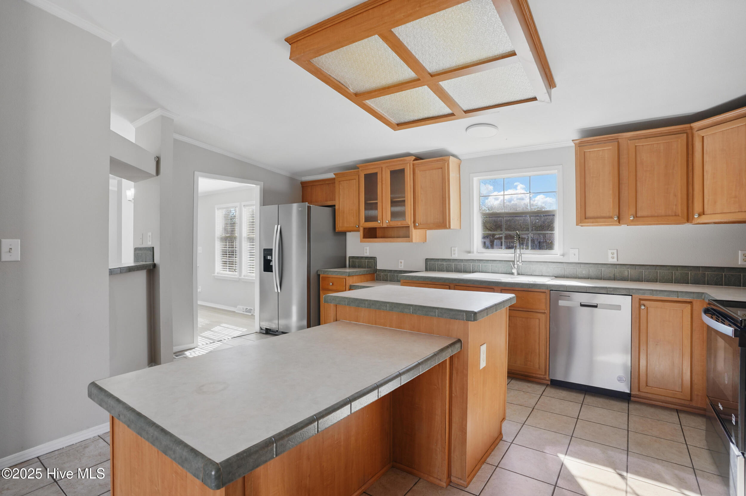 Kitchen with warm wood cabinets, stainless steel appliances, and two breakfast bars.
