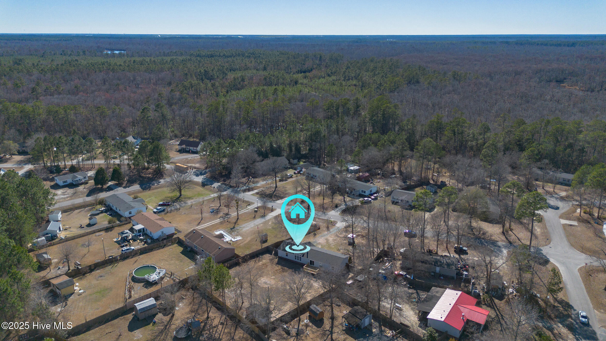 Aerial view of the home marked among neighboring houses and wooded surroundings.