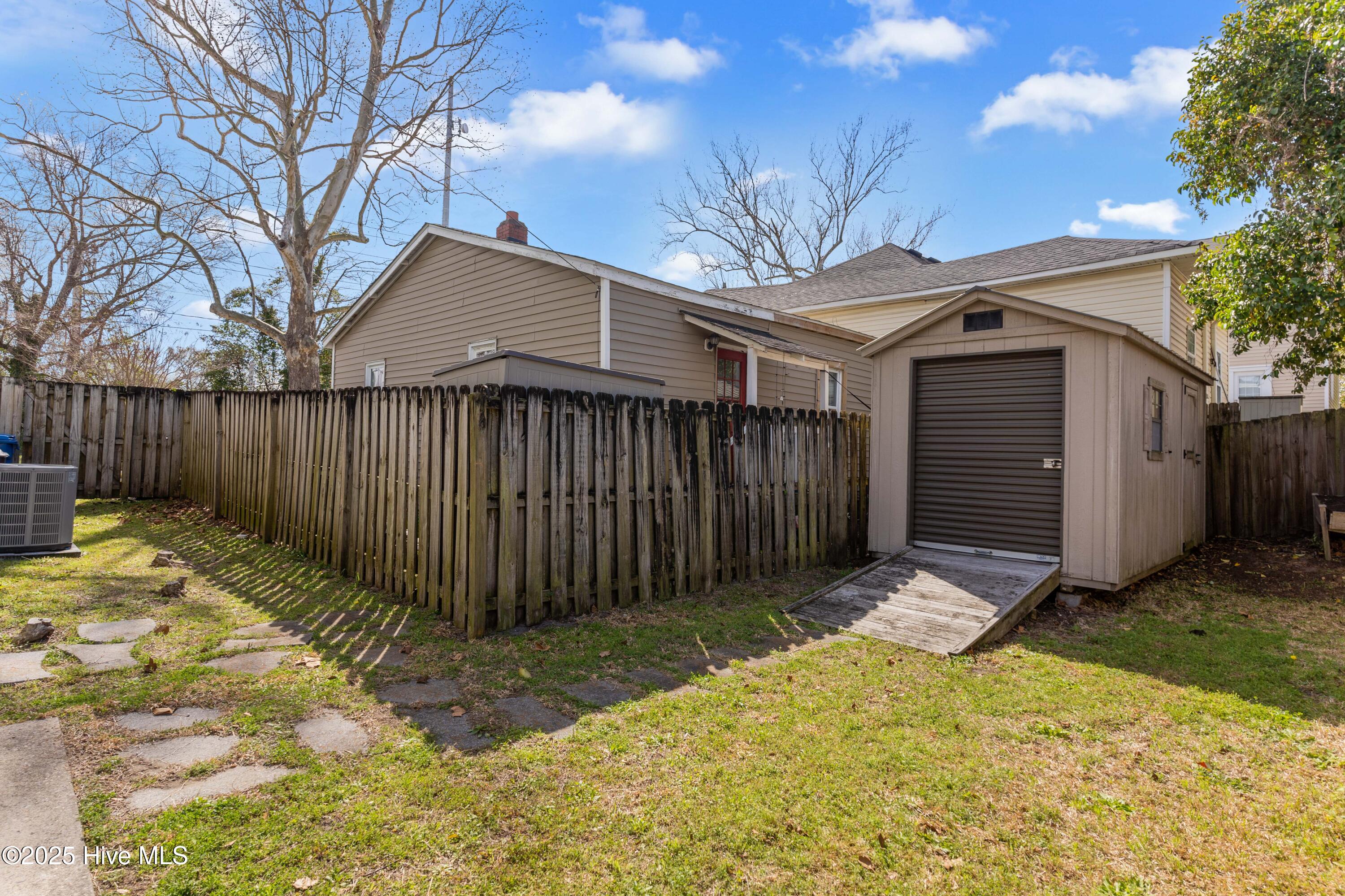Rear exterior with a fenced yard, detached garage, and stepping-stone path.