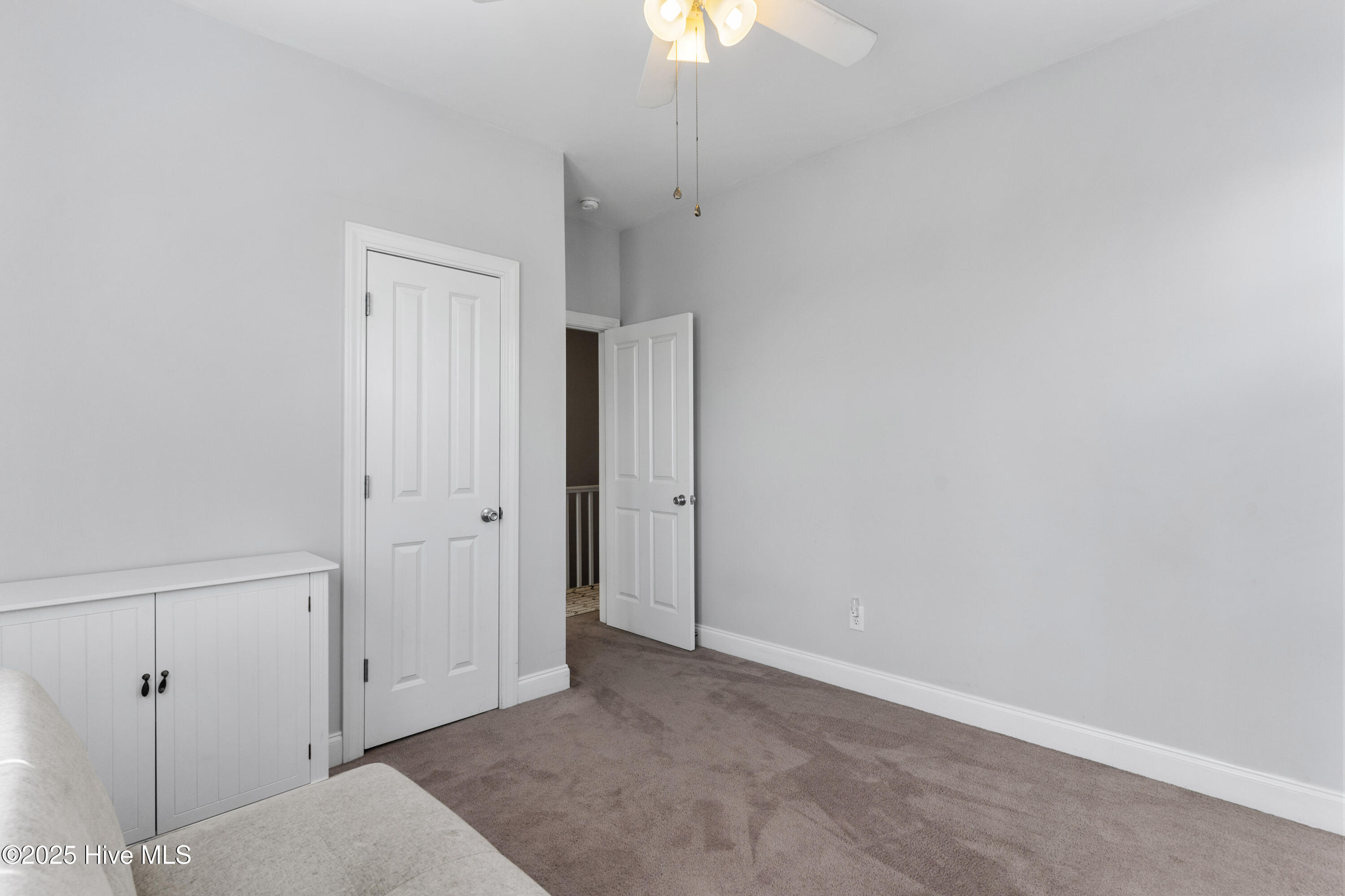 Bedroom with gray carpet, a white cabinet, and two paneled doors.