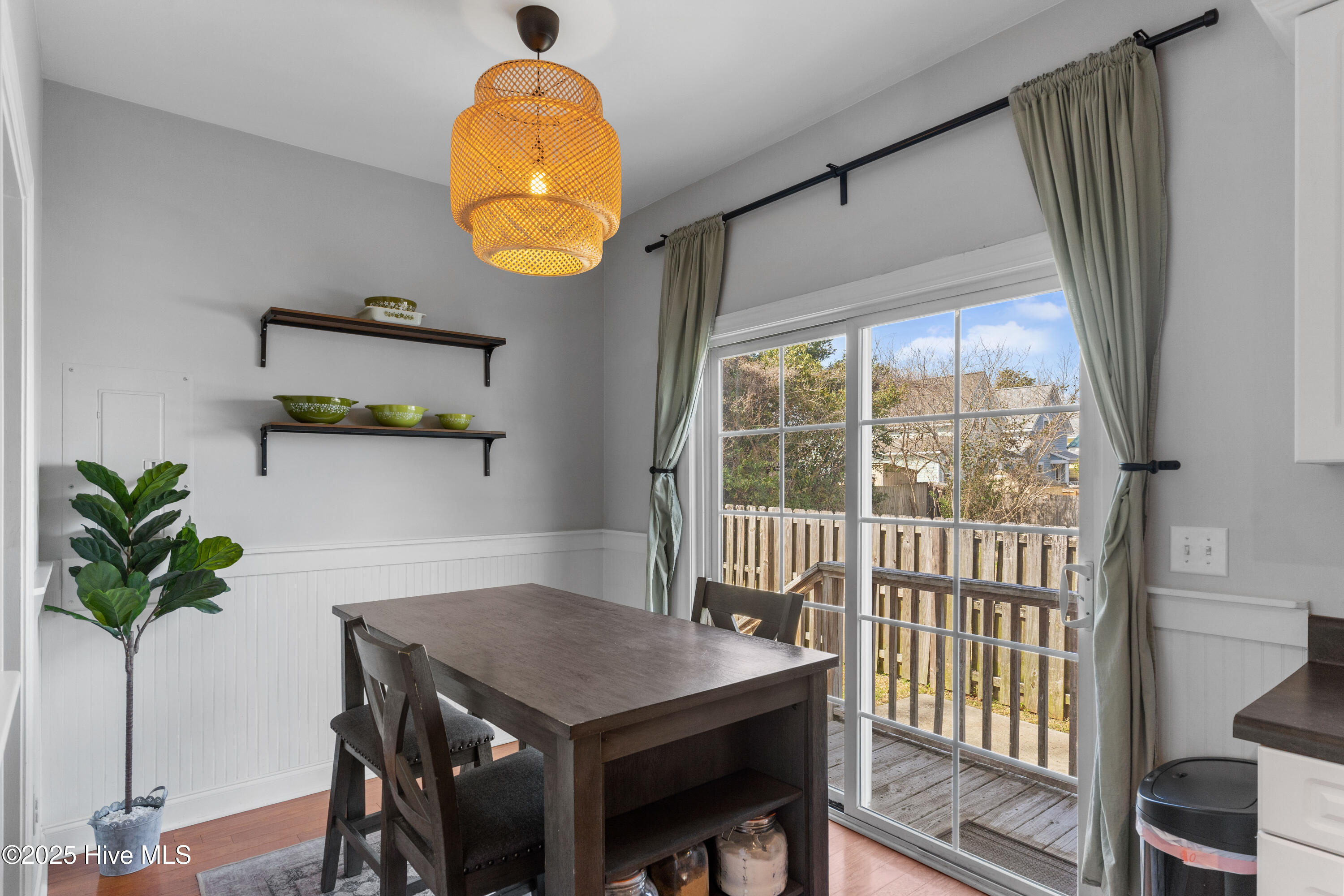 Dining area with a woven pendant light and sliding glass doors opening onto a wooden deck.