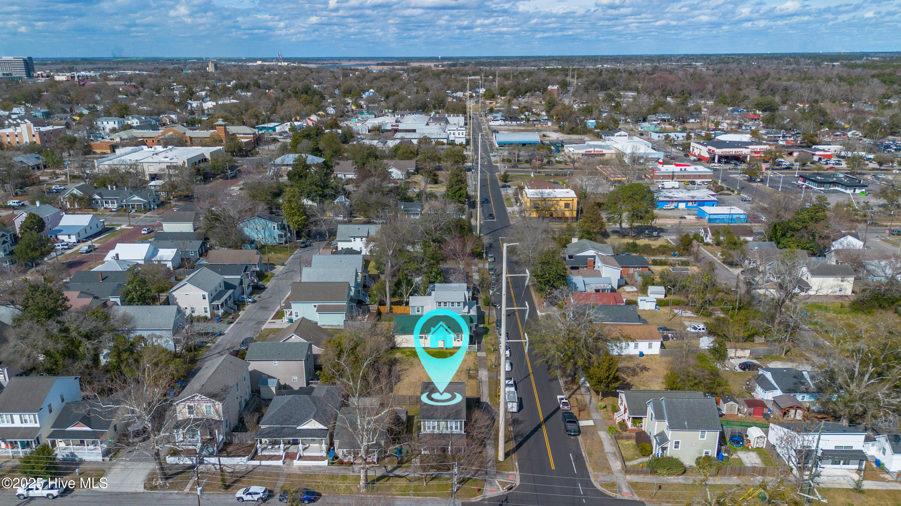 Aerial neighborhood view with a turquoise pin marking a house beside the road.