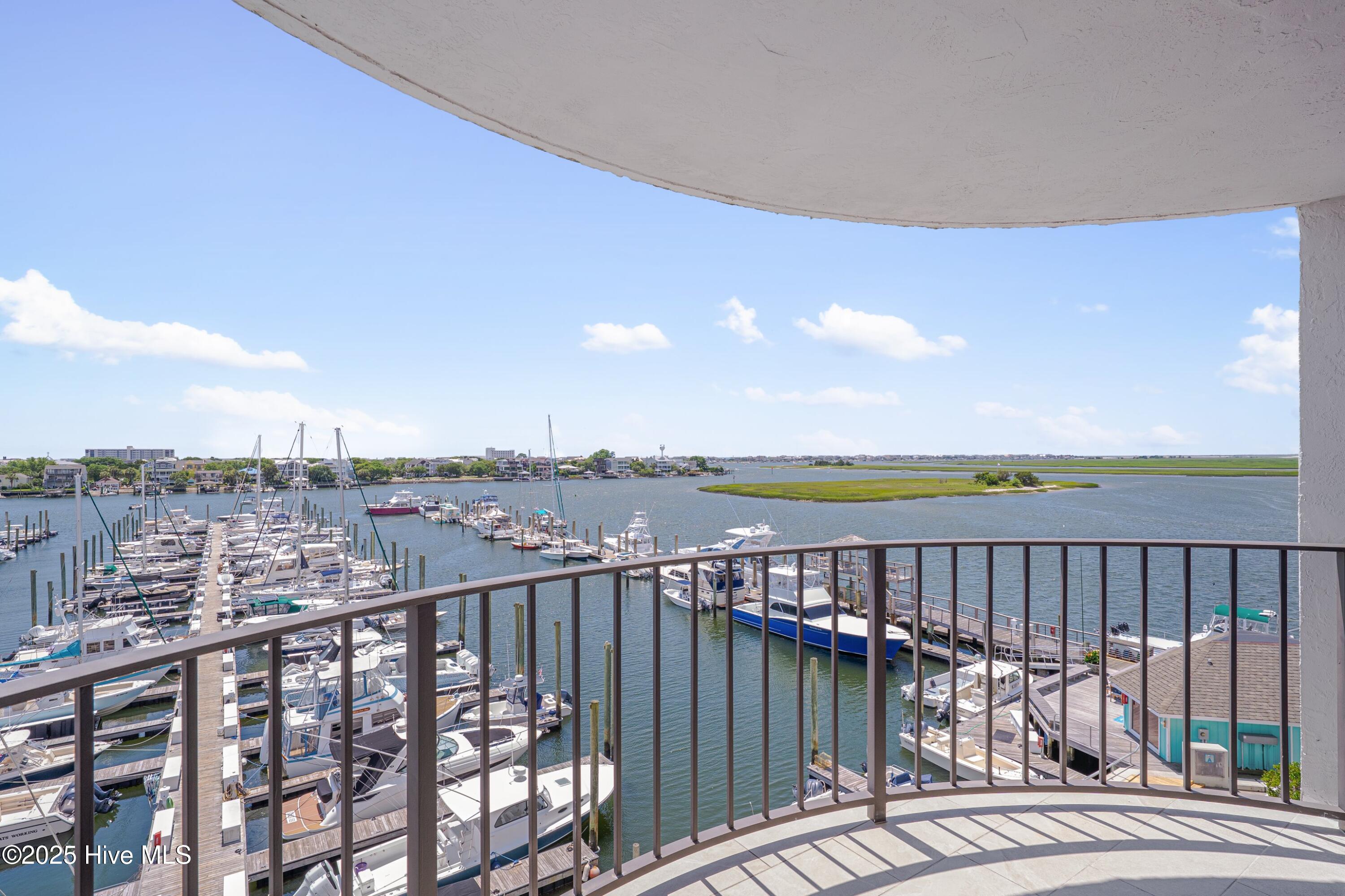 Balcony overlooking a marina crowded with boats, with water and marsh beyond.