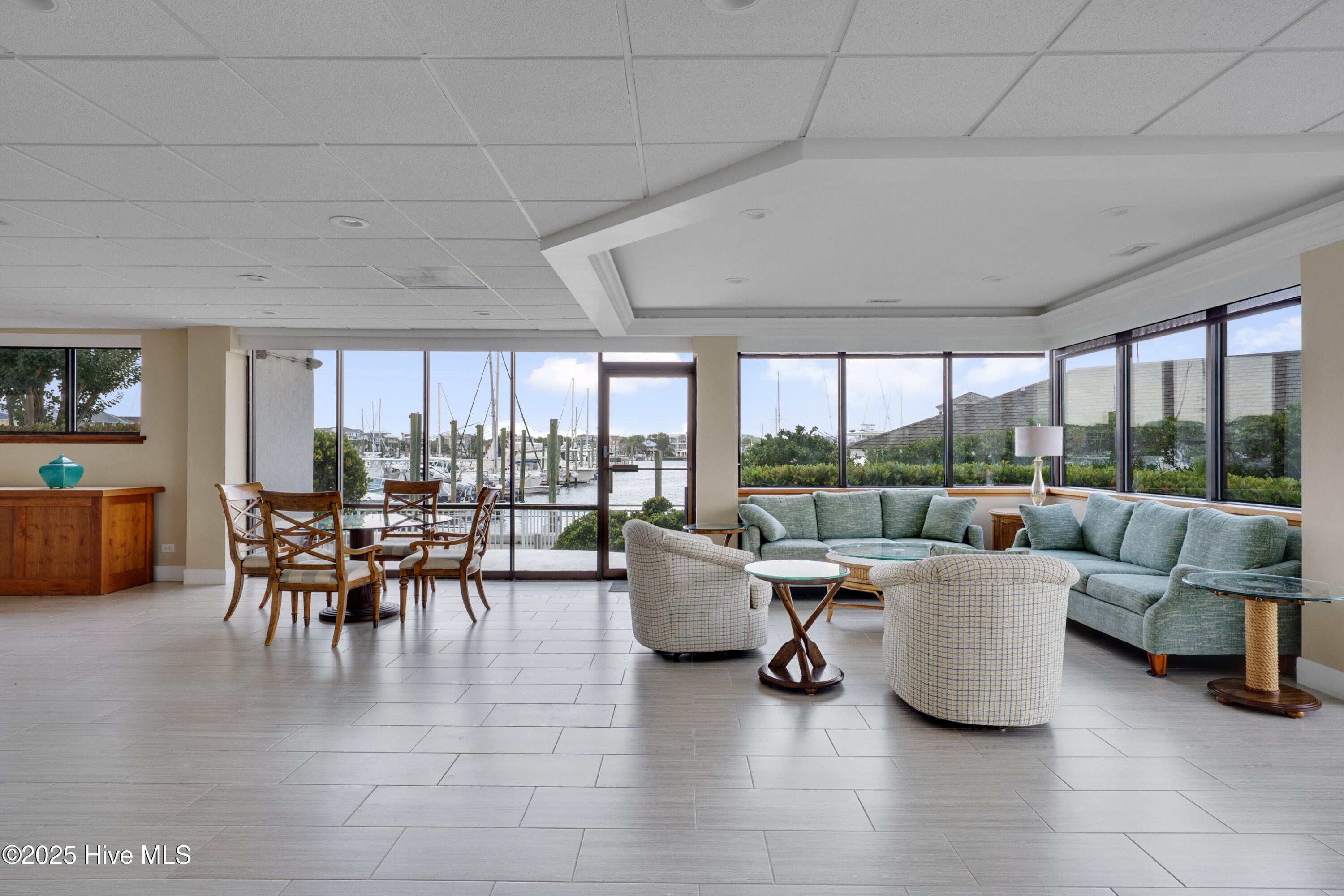 Living room with marina views through wide windows, pale blue sofas, and patterned armchairs.