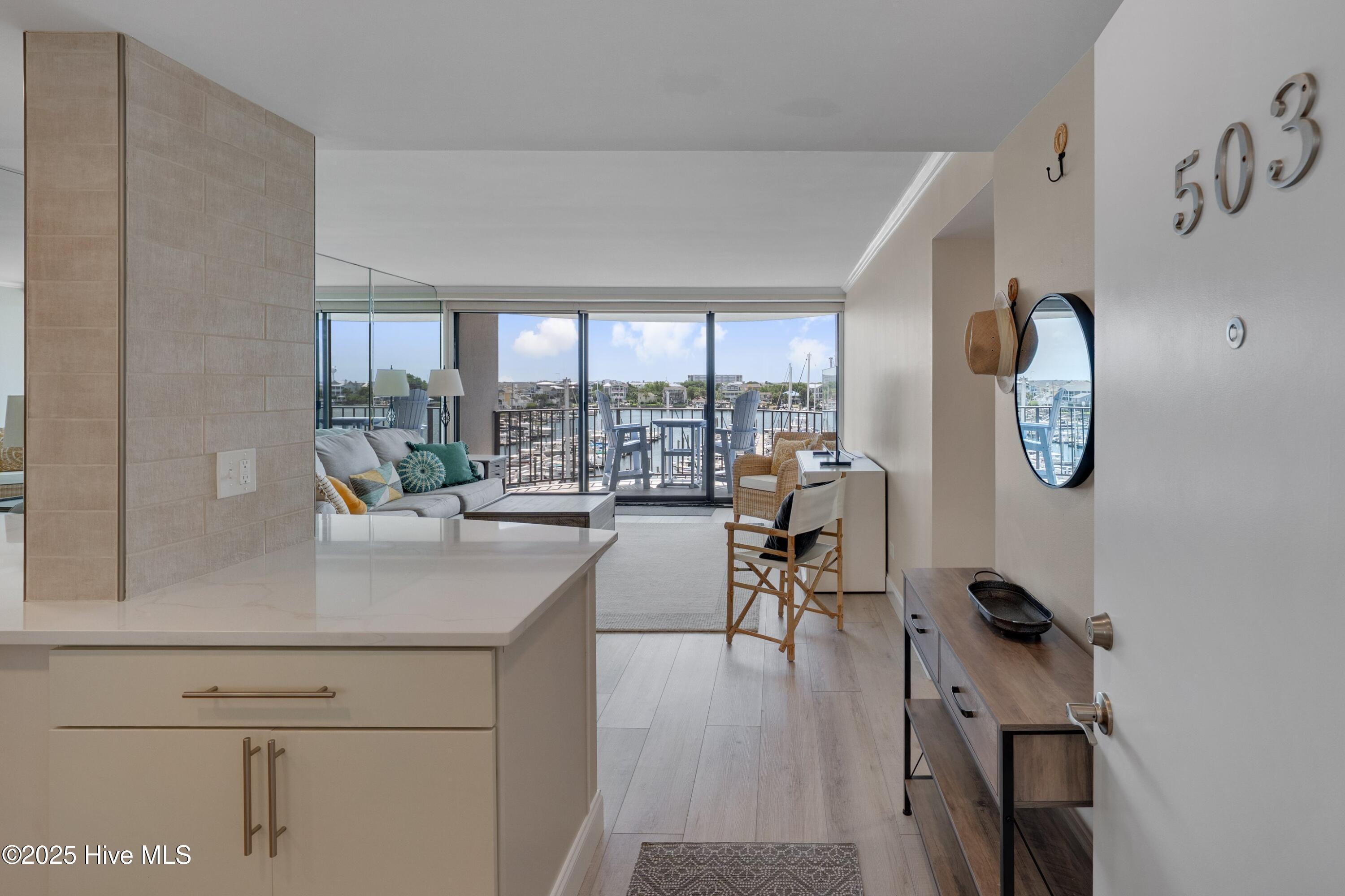 Open-plan condo living room with a furnished balcony overlooking a marina.