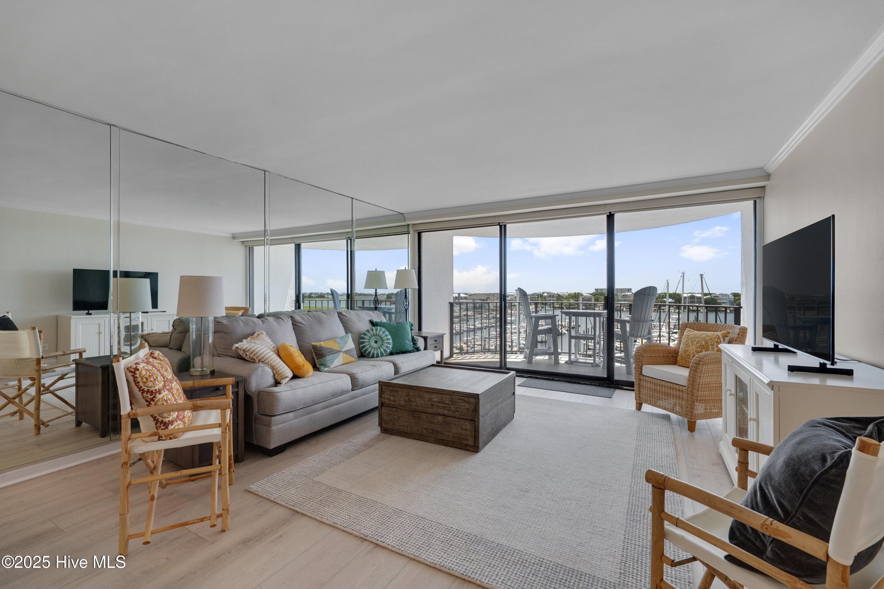 Living room with gray sectional and glass doors opening to a marina-view balcony.