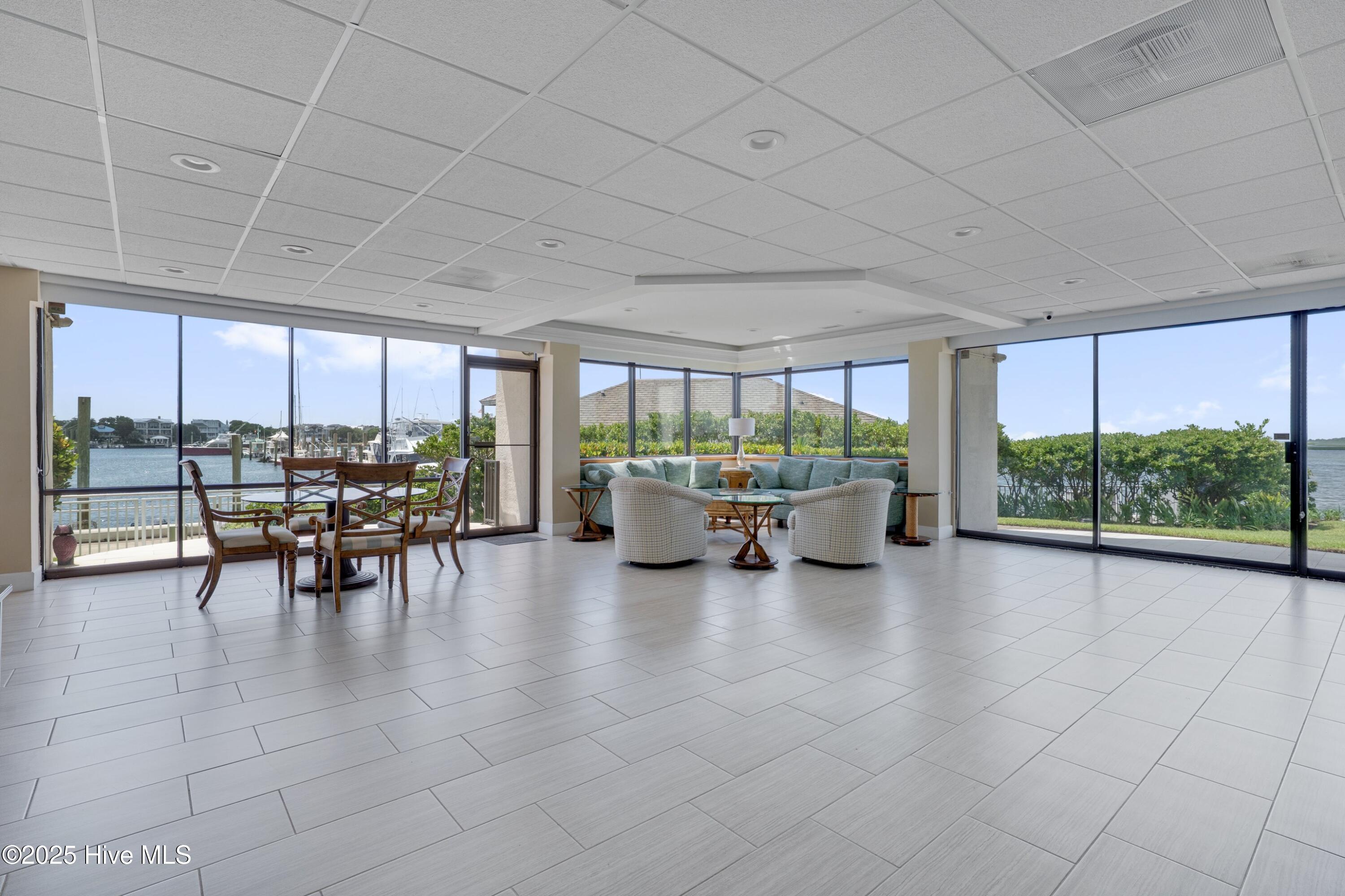Waterfront condo living and dining area with full-height windows overlooking a marina.