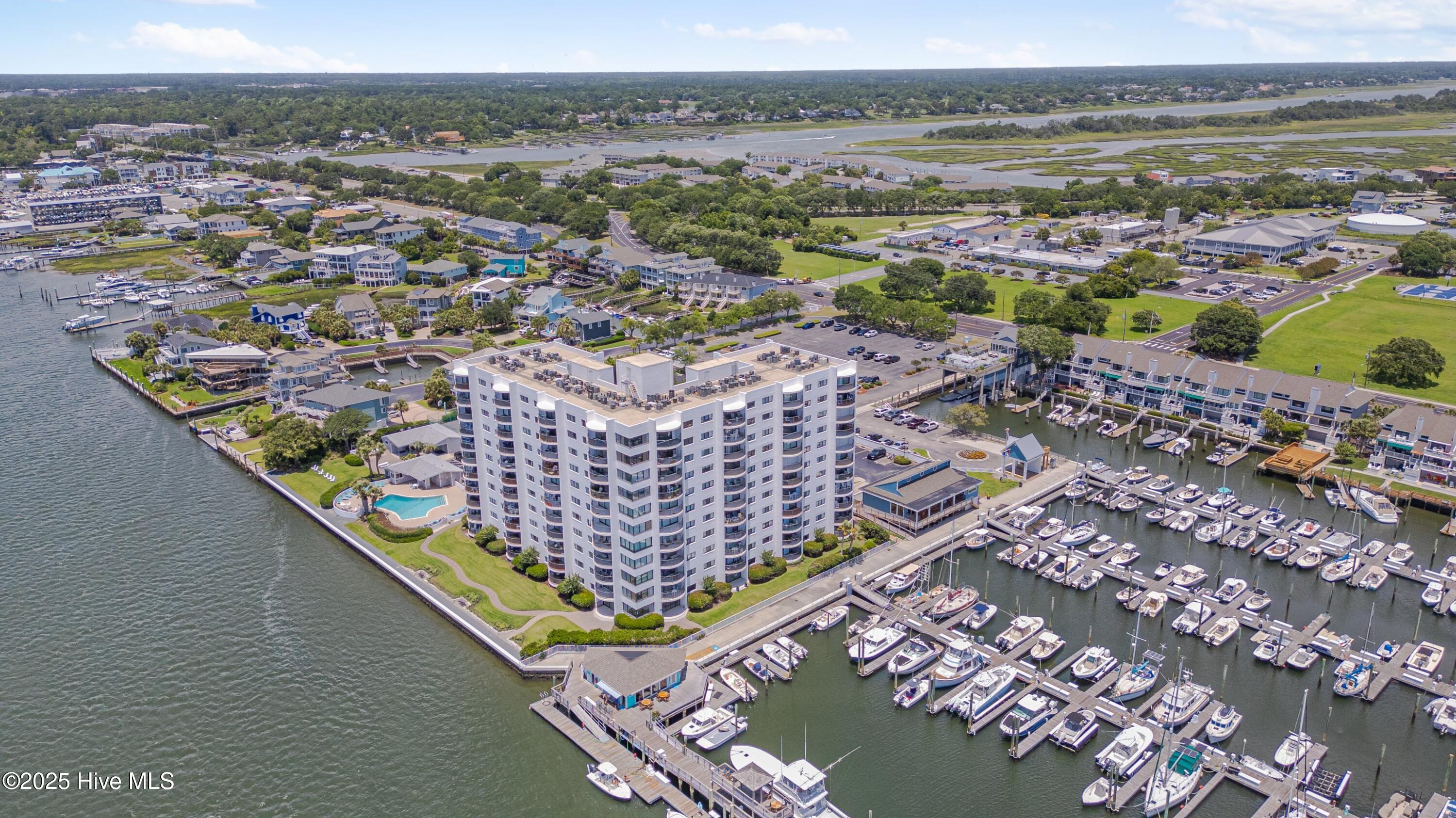 Waterfront condominium beside a marina, with a pool and boats docked along the surrounding waterways.