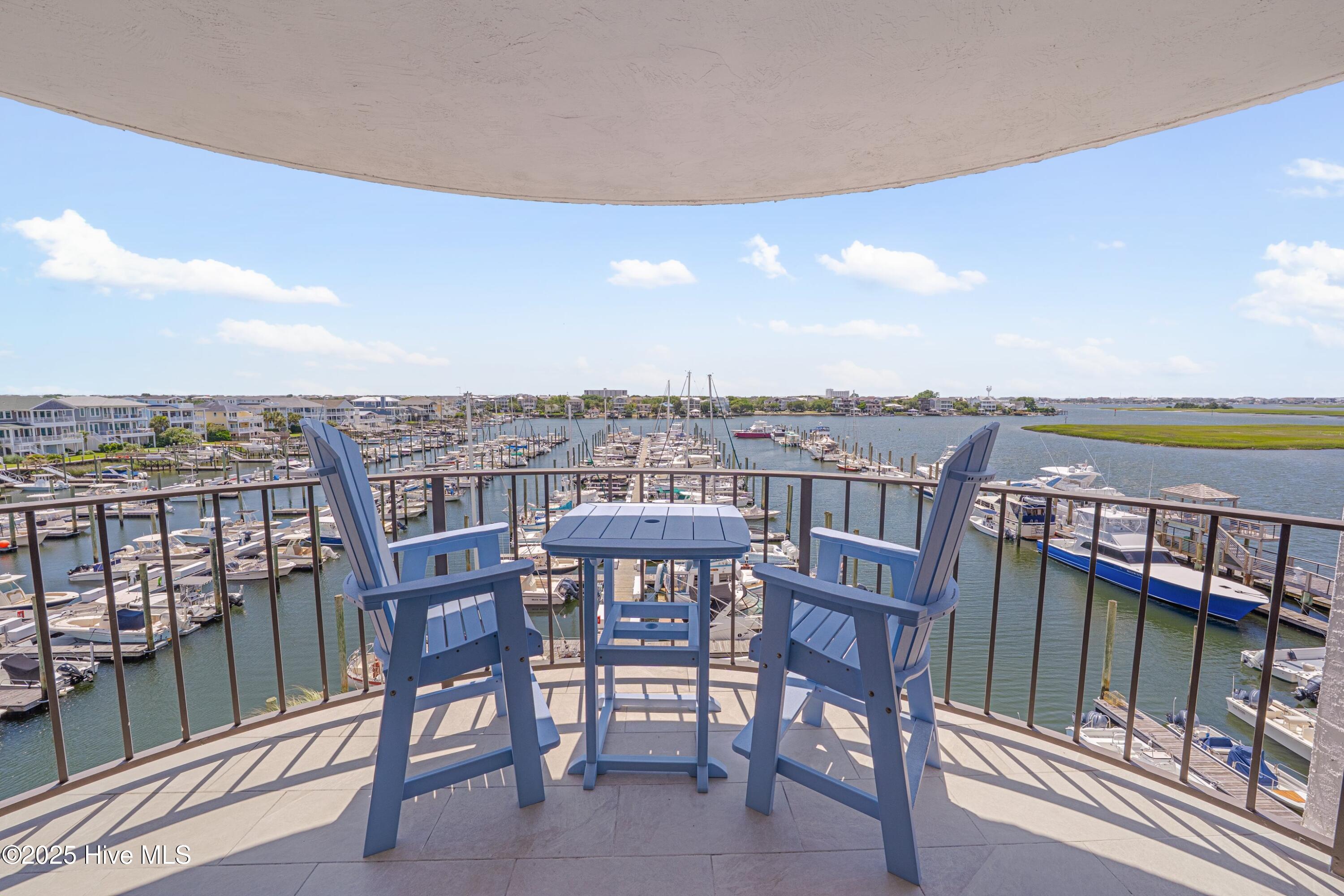 Balcony seating overlooks a marina crowded with boats, waterfront homes, and marshland.