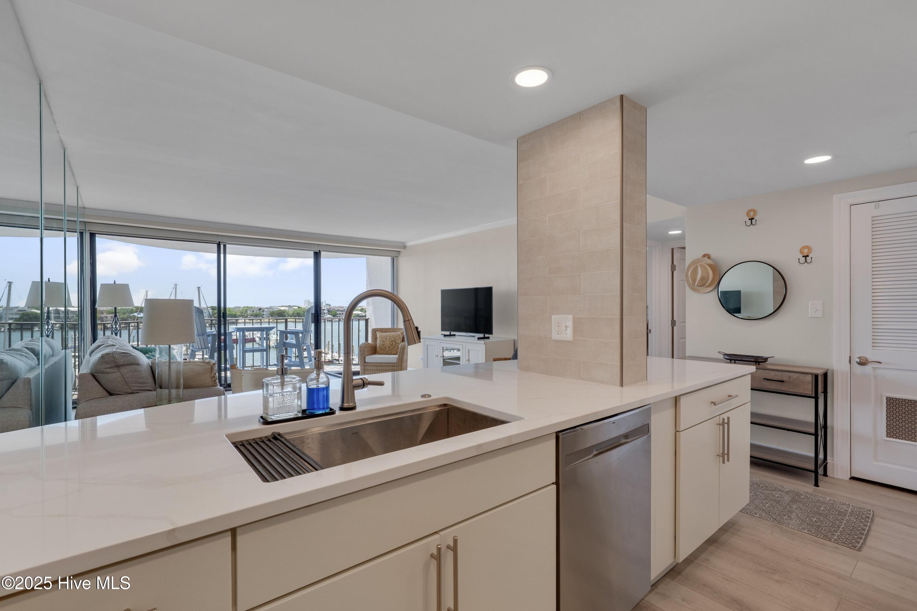 Open-plan kitchen with a white island and sink, overlooking a furnished living area and water.