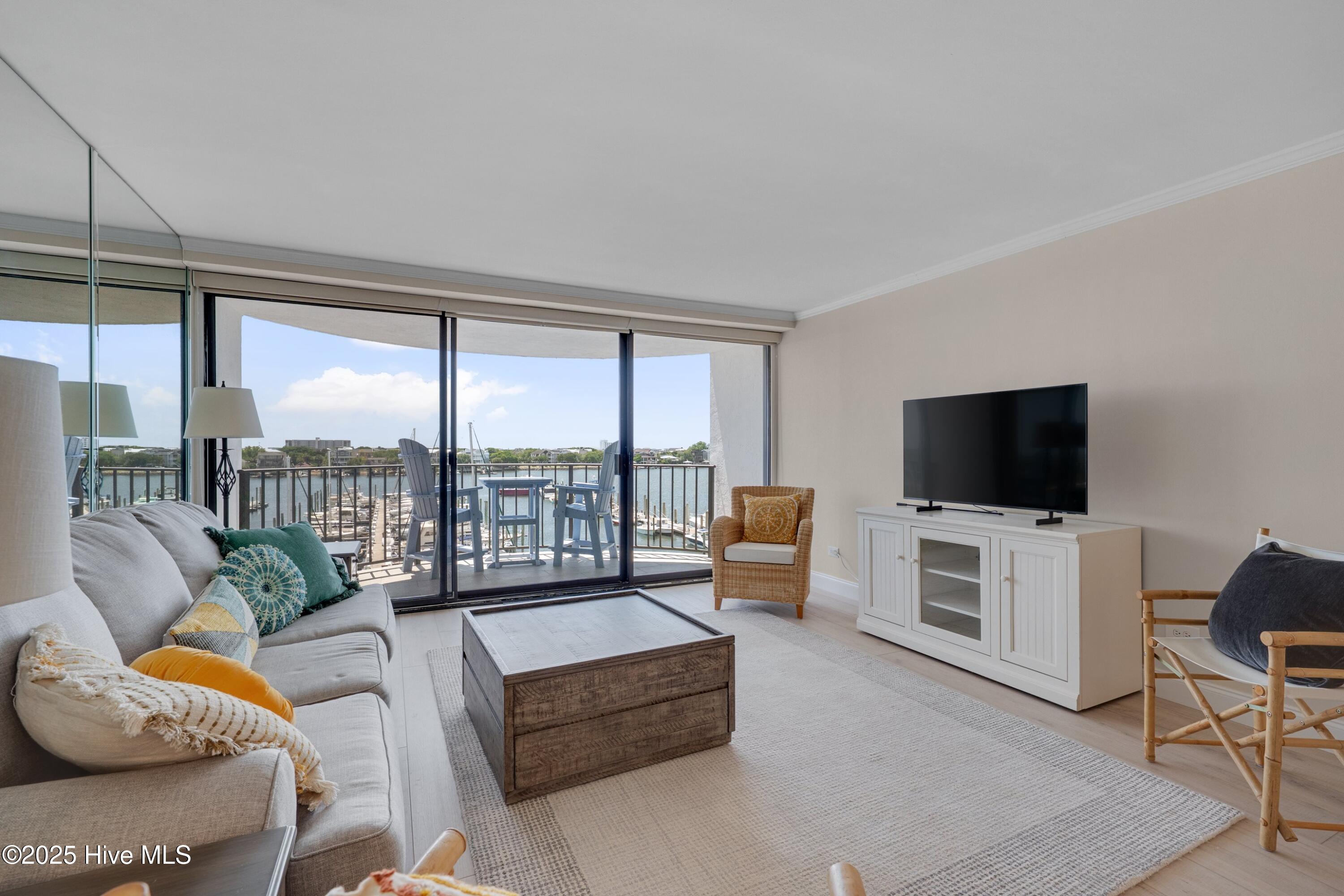Furnished living room with sliding glass doors overlooking a marina and water.
