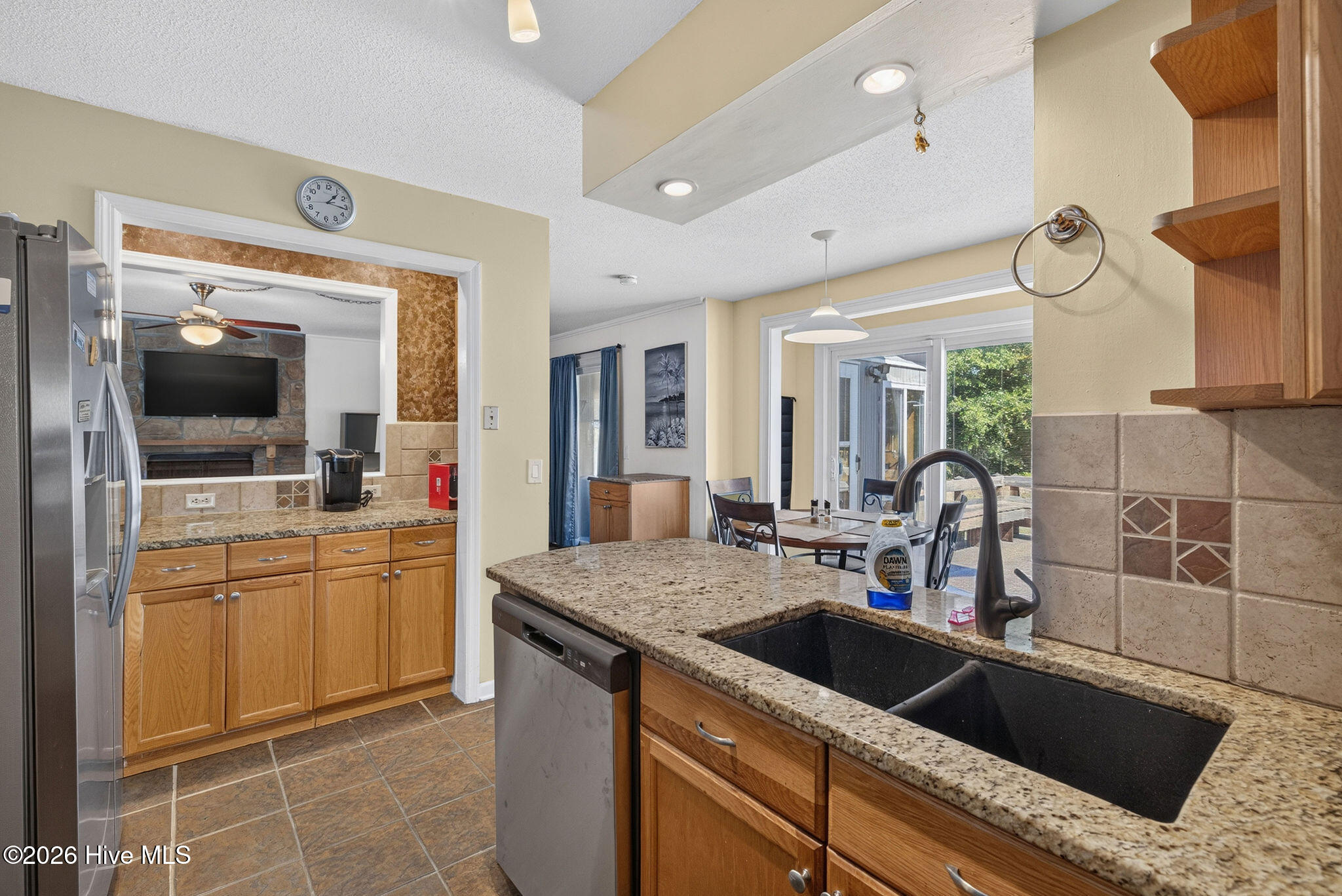 Kitchen with granite counters and black sink opening to a dining area and living room.