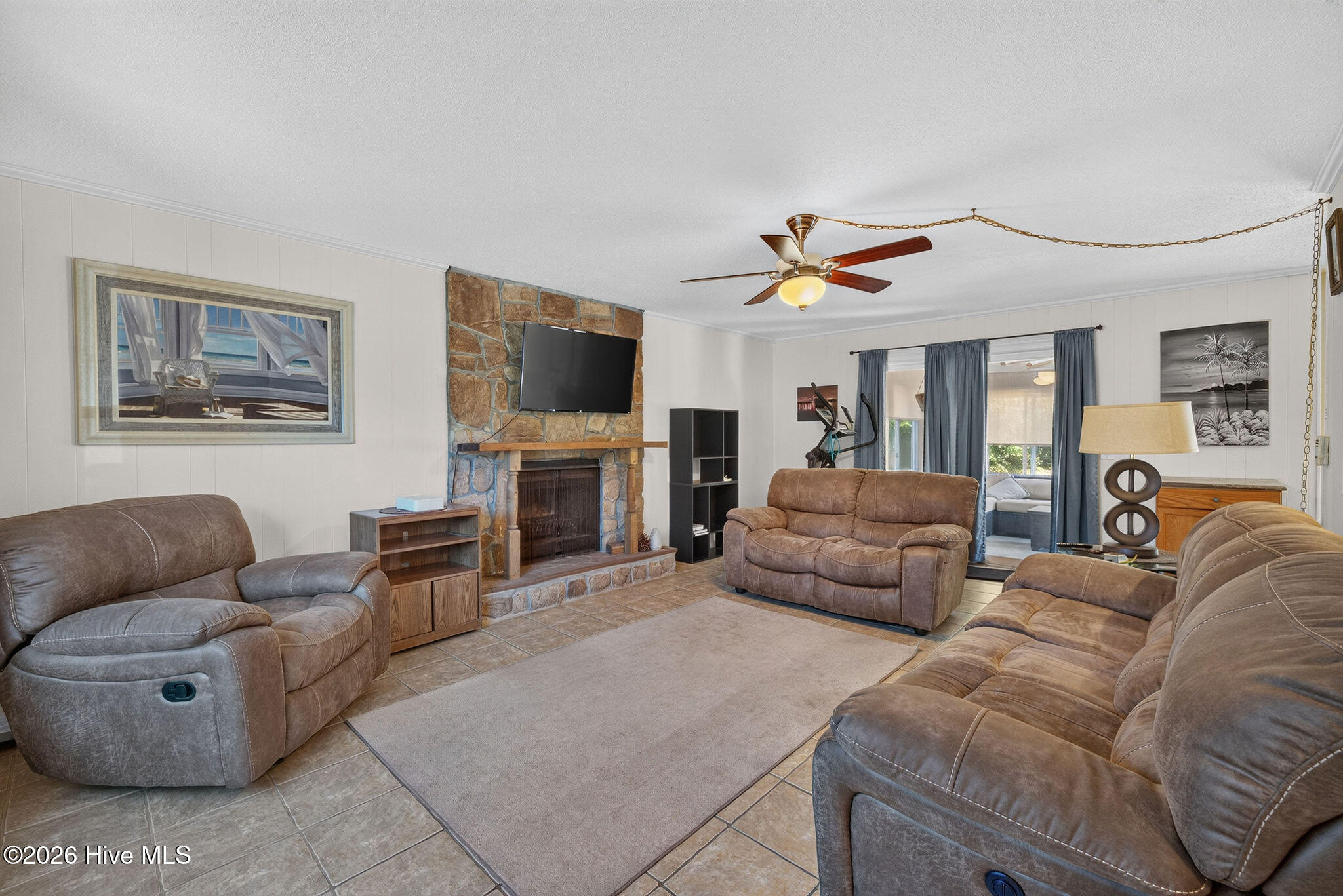 Furnished living room with brown leather sofas and a stone fireplace.