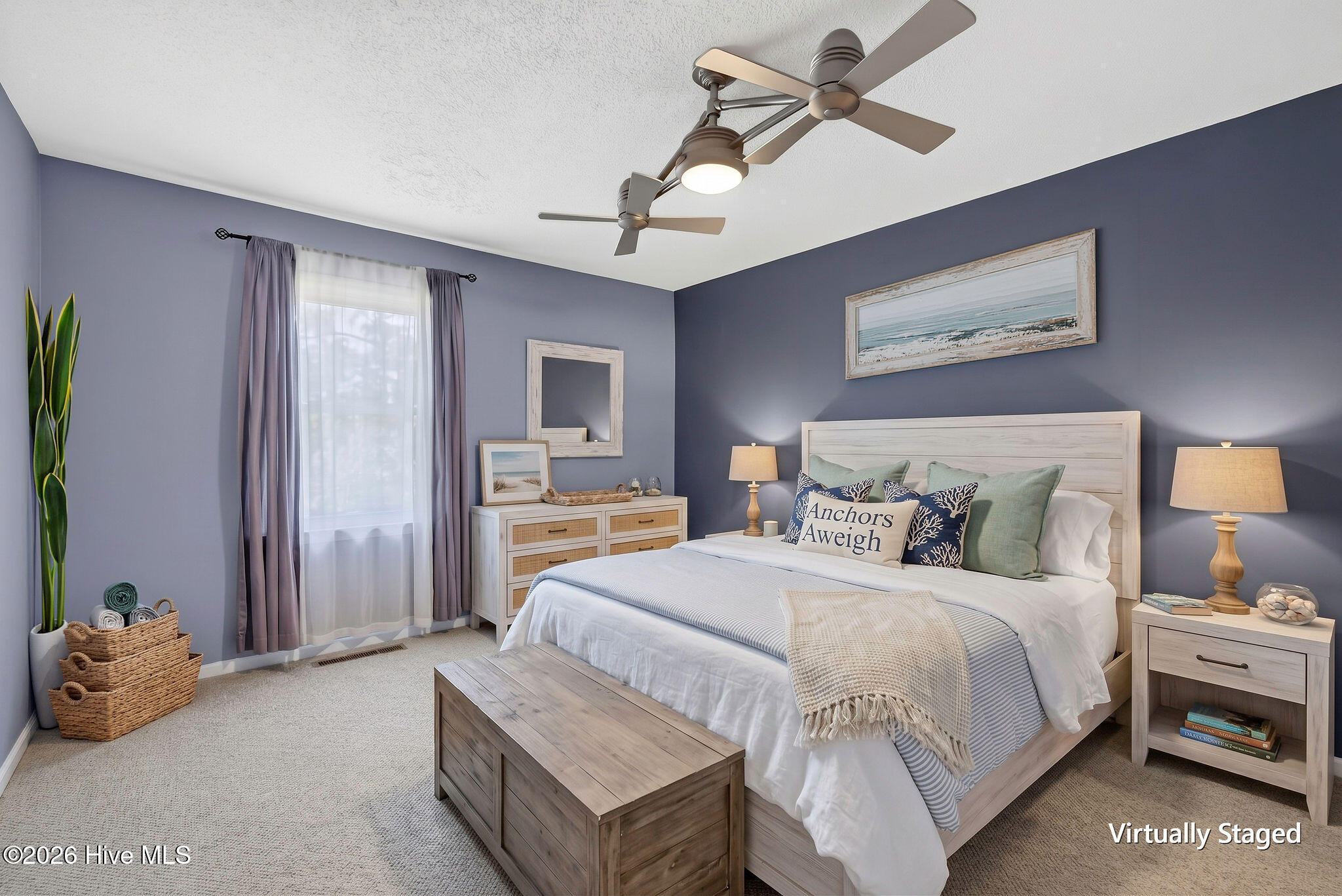 Bedroom with coastal-themed bedding, lavender-gray walls, and a light wood bed and matching furniture.