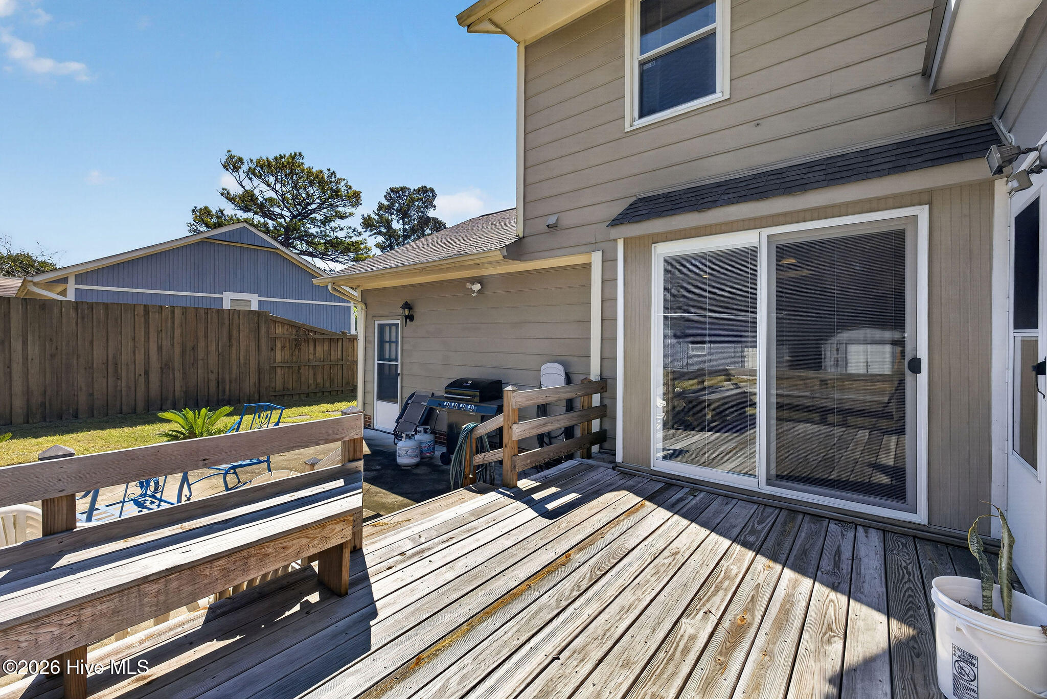 Back deck with weathered wood boards, sliding glass doors, and a covered grill area.