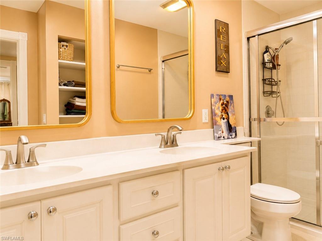 Bathroom with a double-sink vanity, gold-framed mirrors, and a glass-enclosed shower.