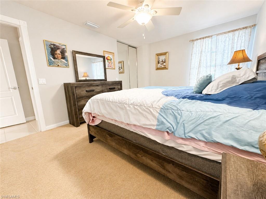 Bedroom with a large blue-and-white bed, dark wood dresser, and ceiling fan.