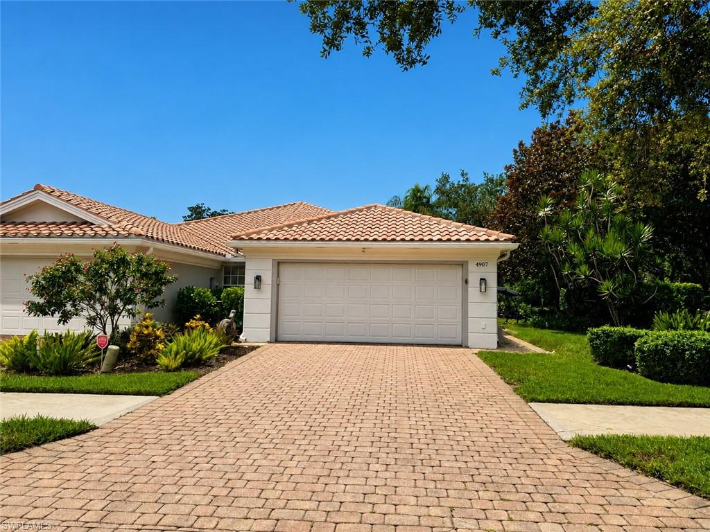 Single-story home with a terracotta tile roof, double garage, and brick-paver driveway.