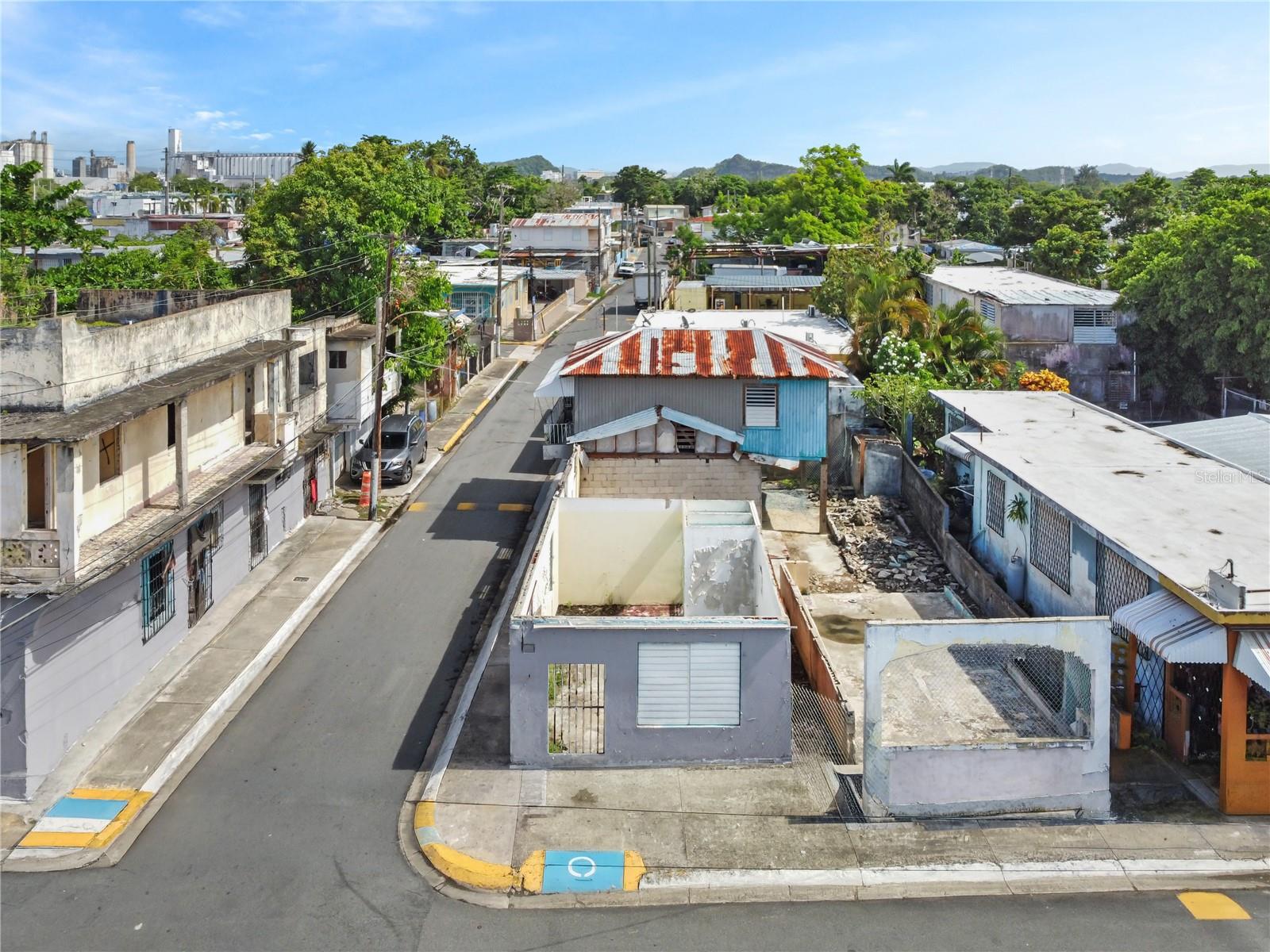 Aerial view of a residential street with a blue-and-white building and rusted metal roof.