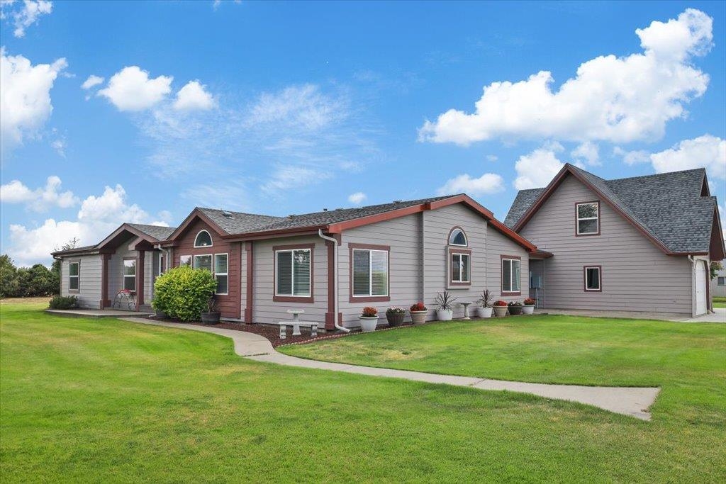 Gray home with red-brown trim, a taller gabled section, and a curved walkway across the lawn.