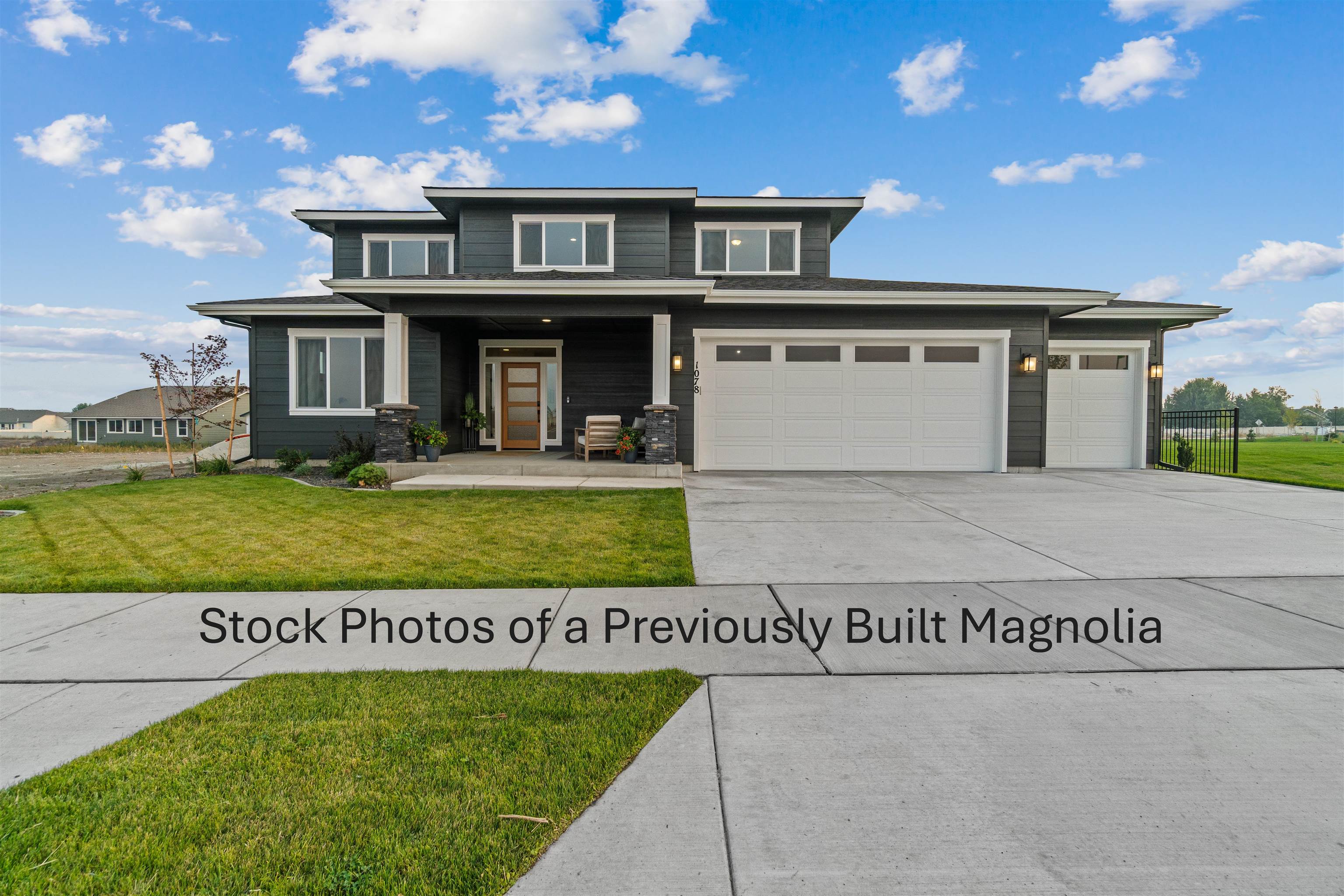 Modern dark gray two-story house with white trim, two garage doors, and a covered entry.