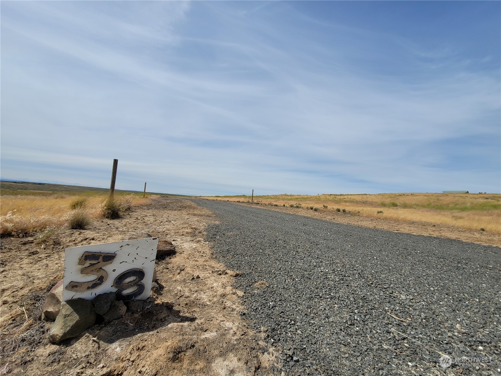 Open grassland lot with a gravel access road and a marker numbered 38.