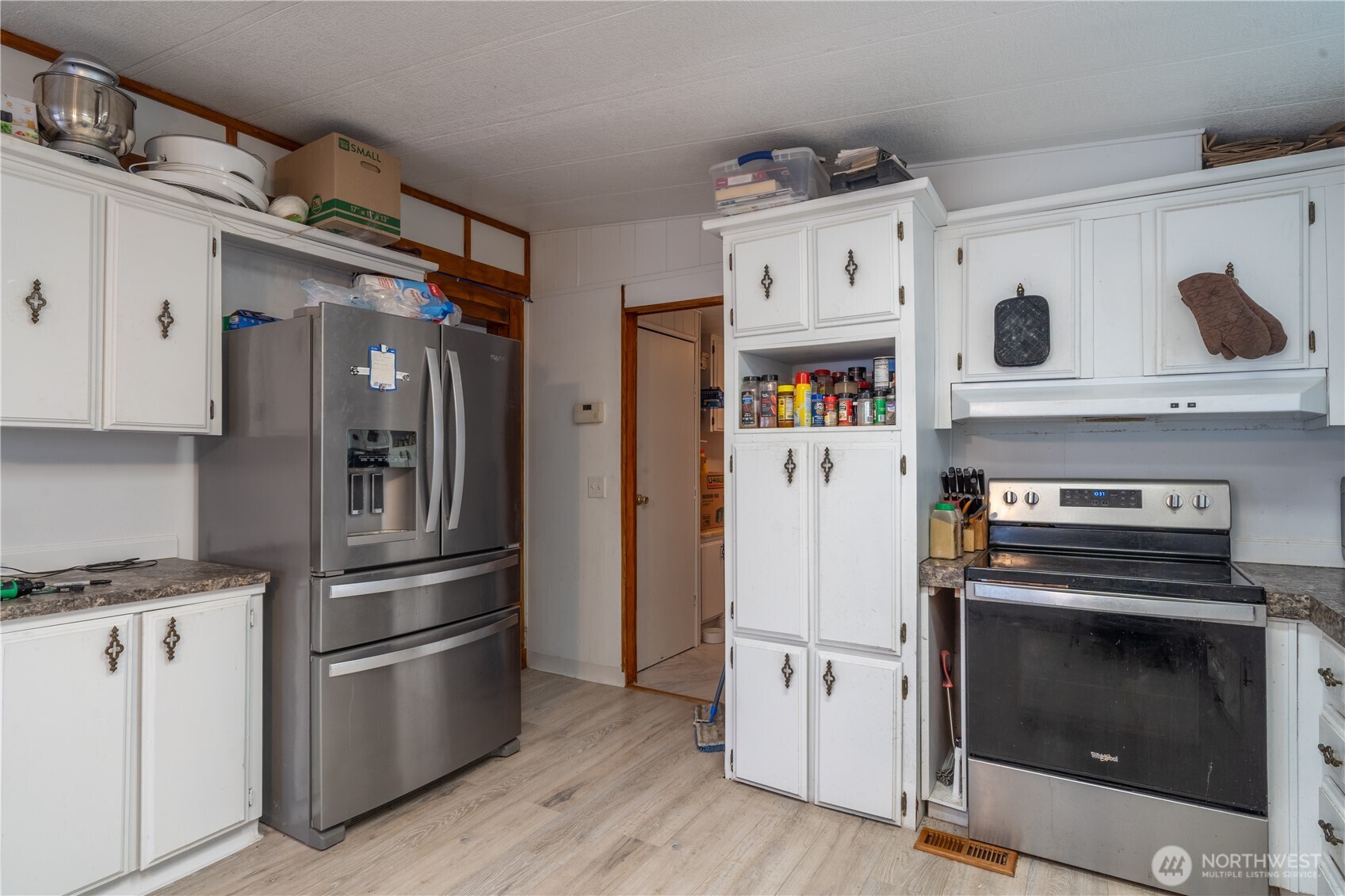 Kitchen with white cabinets, stainless steel refrigerator, and black range.