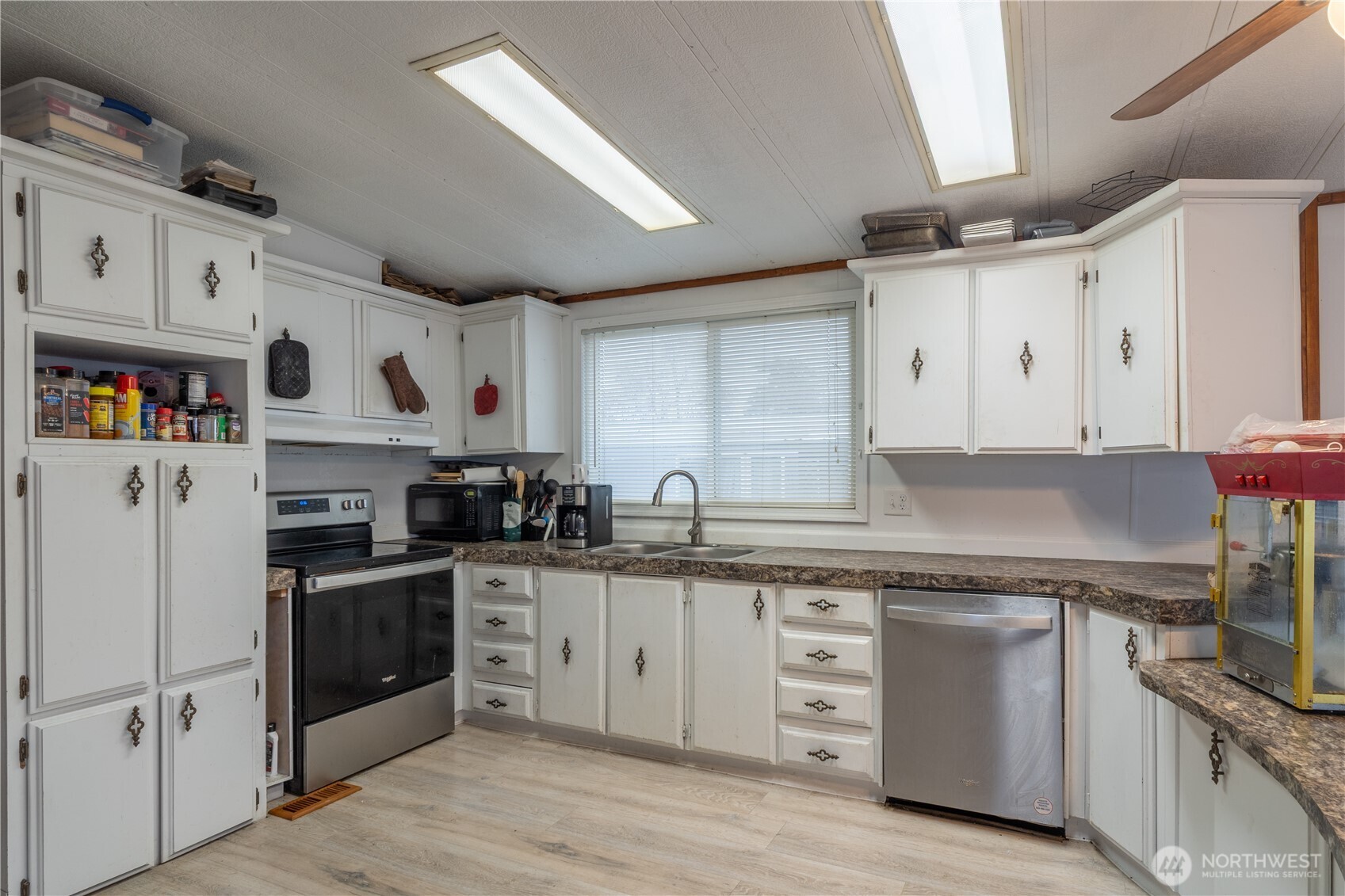 Kitchen with white cabinets, a window over the sink, and a stainless steel dishwasher.