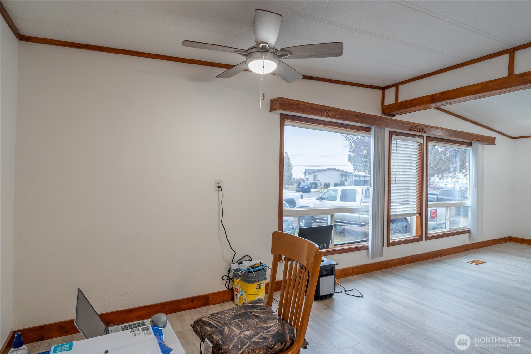 Living room with dark wood trim, large windows, and a ceiling fan.