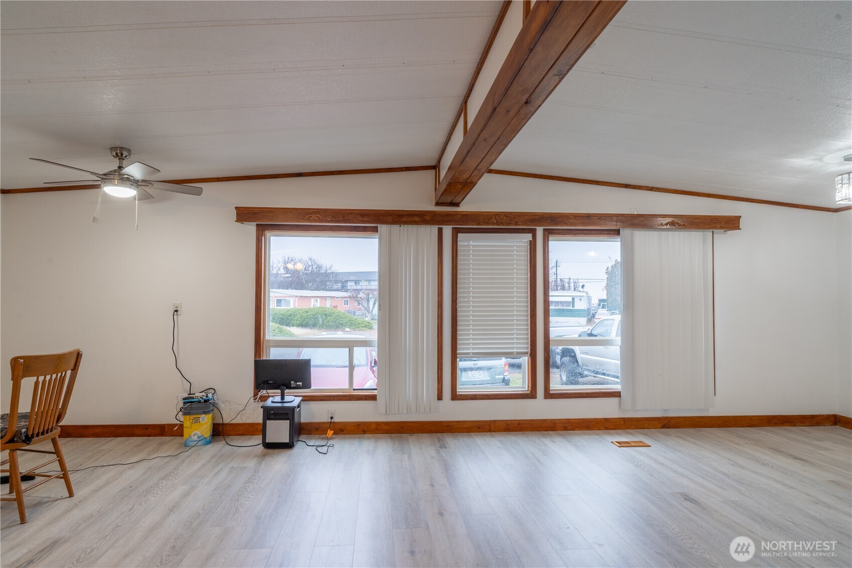 Living room with a vaulted ceiling, exposed wood beams, and broad wood-trimmed windows.