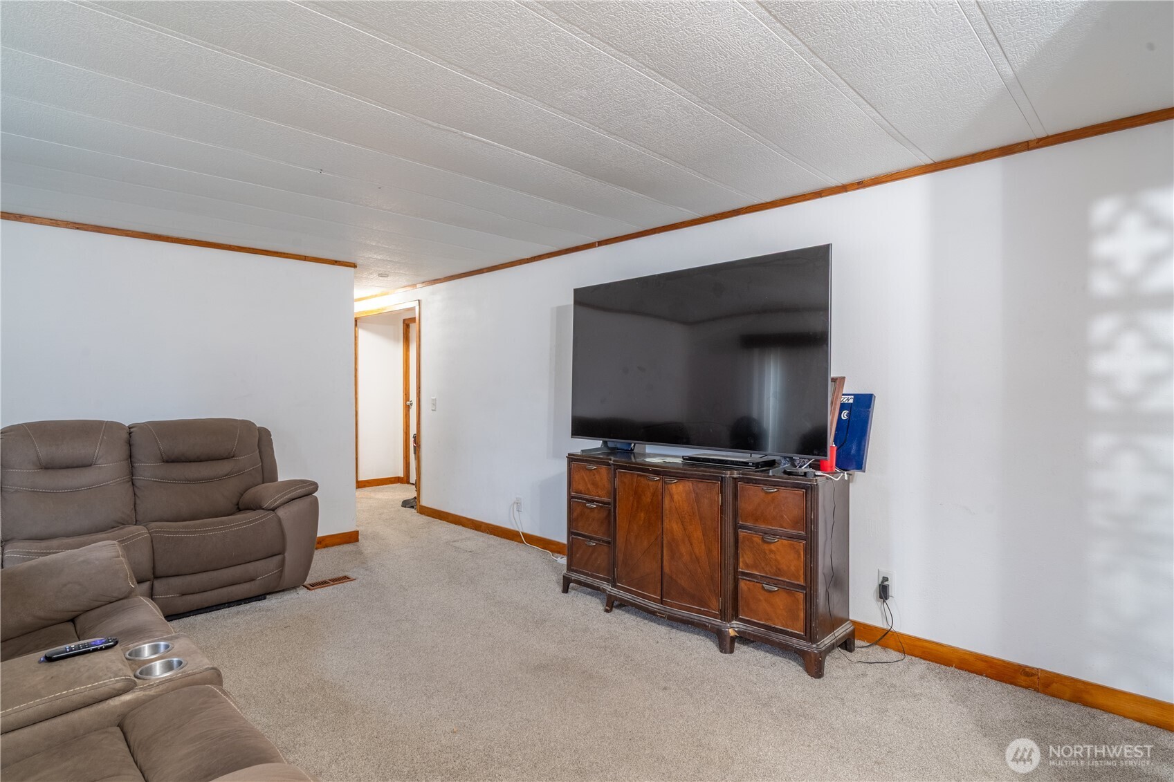 Living room with reclining sofas and a large television on a wooden cabinet.