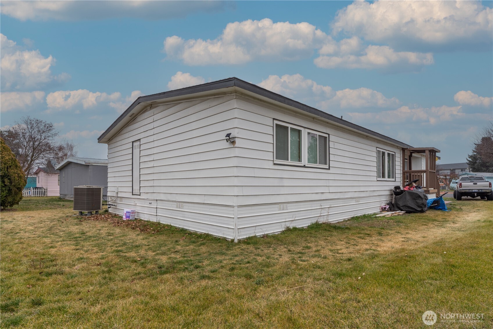 White single-story manufactured home with a small covered porch and lawn.