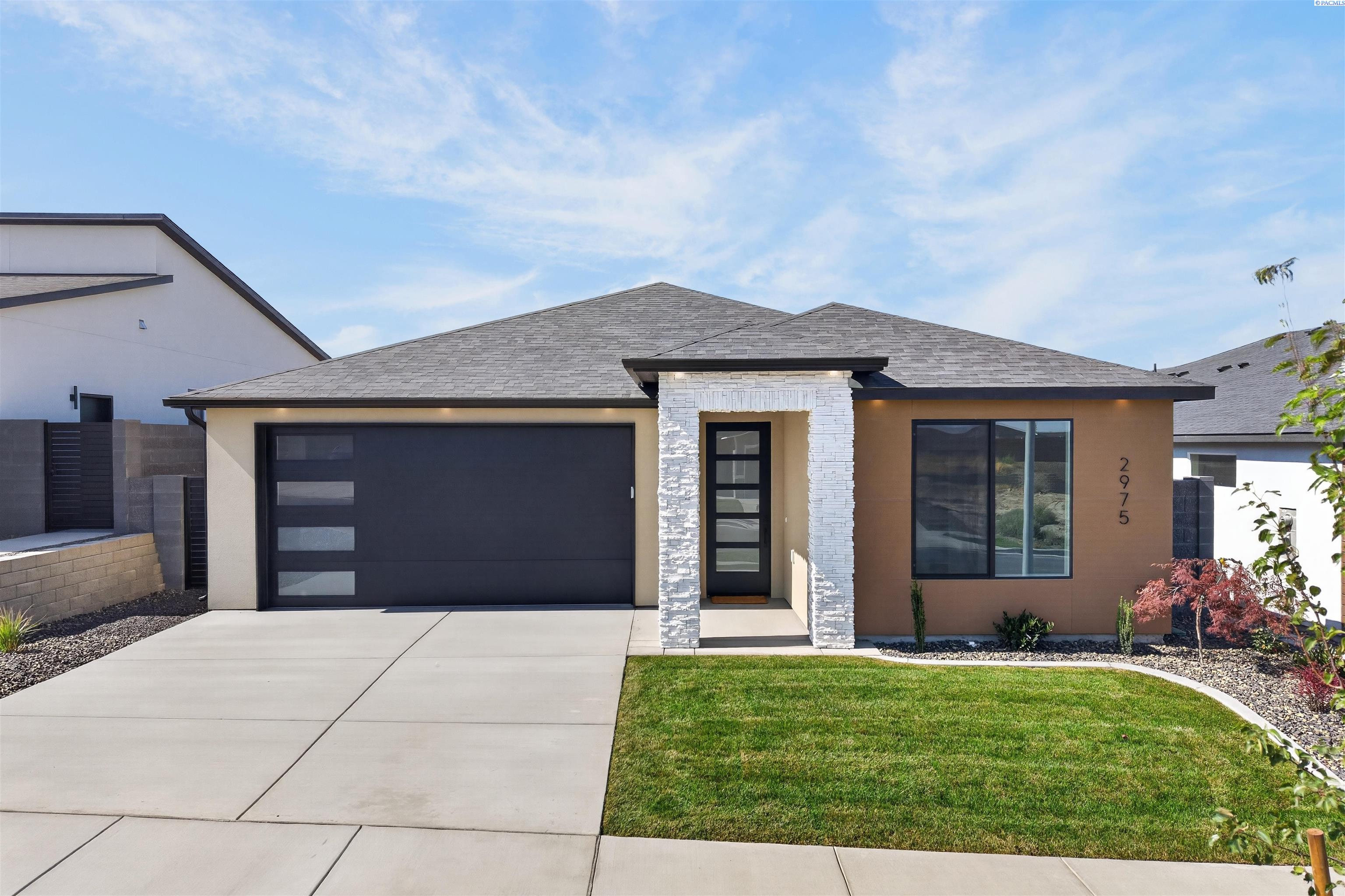 Modern single-story home with stone entry columns, a dark double garage, and landscaped lawn.