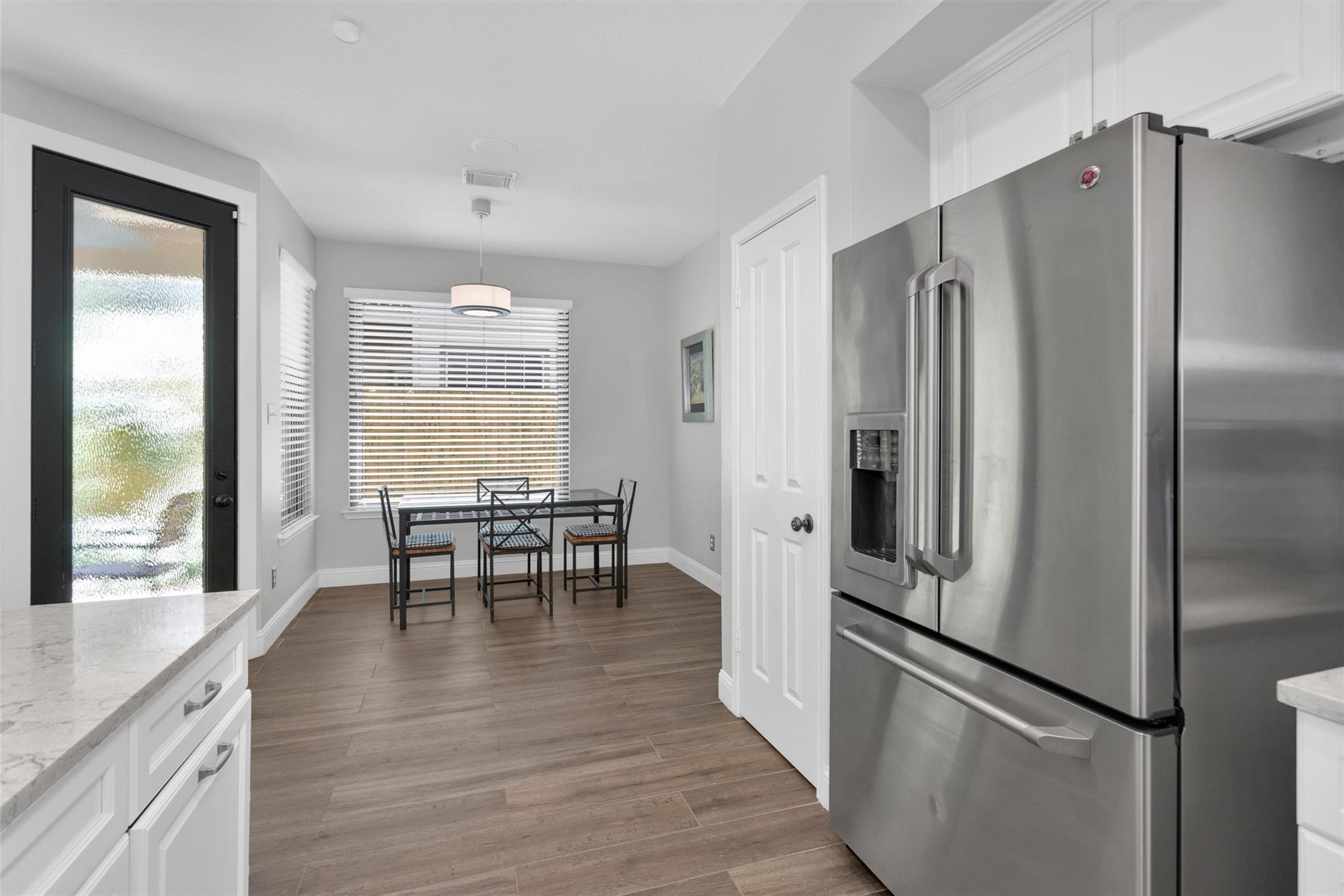 Kitchen dining nook with a stainless steel refrigerator and a small table by the windows.