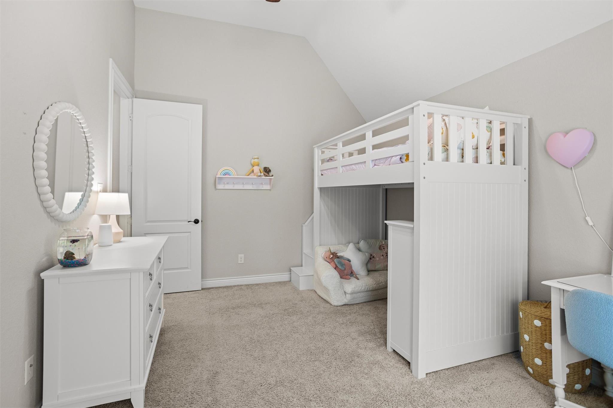 Child's bedroom with a white loft bunk bed and a cushioned nook underneath.