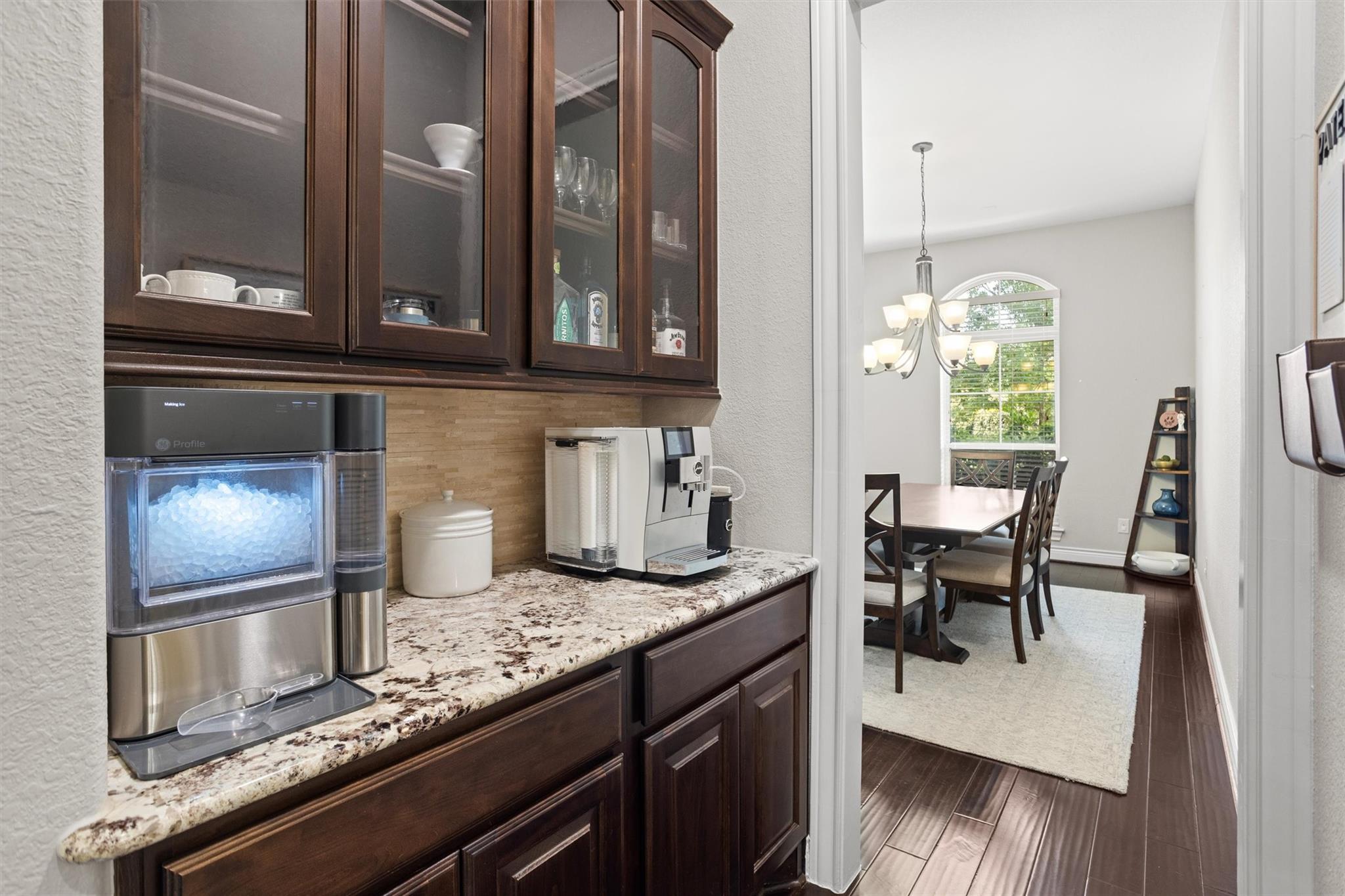Kitchen coffee station with dark wood cabinets and granite counter opening onto a dining room.