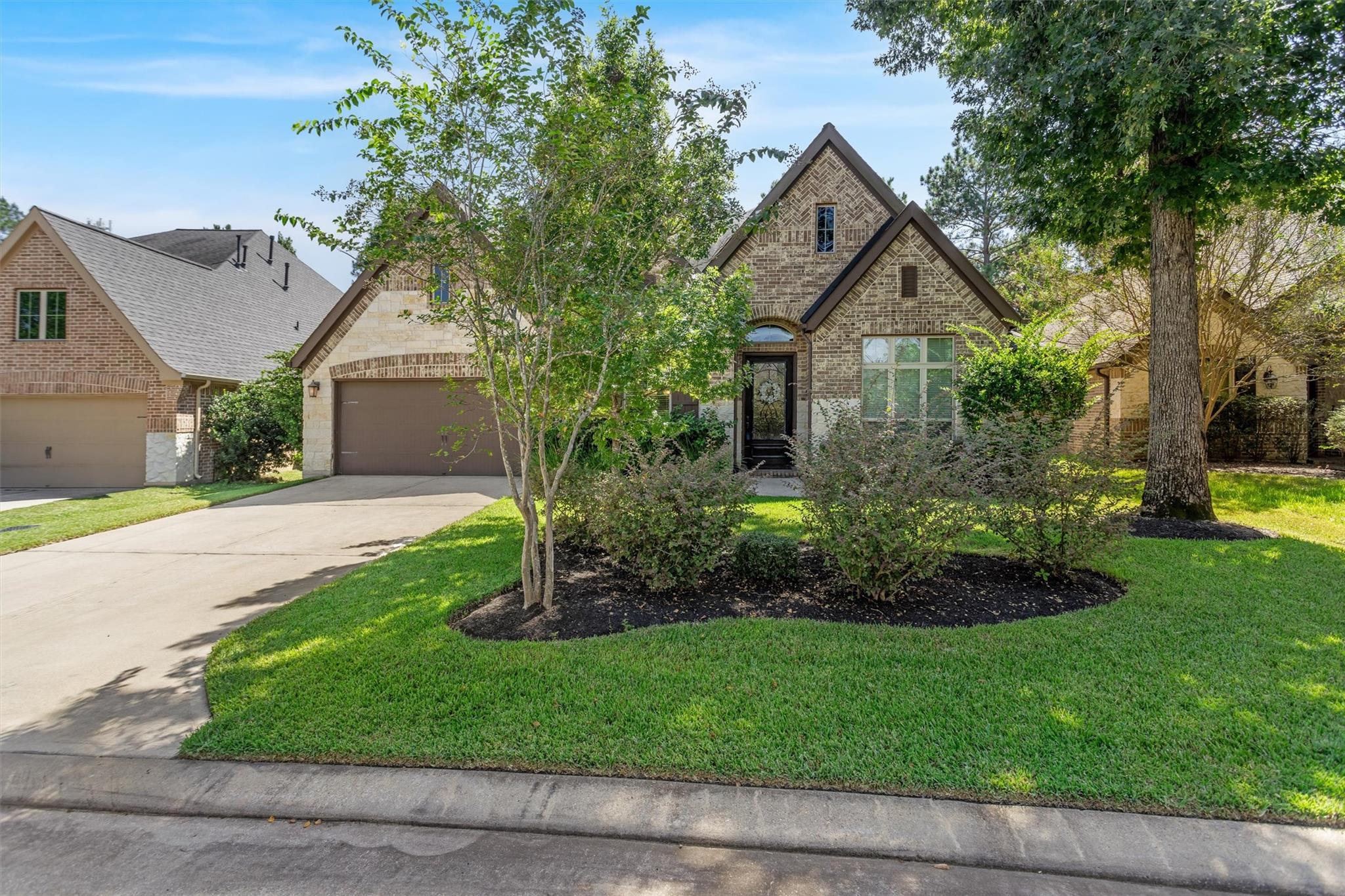 Brick home with steep front gables, attached garage, and landscaped lawn.