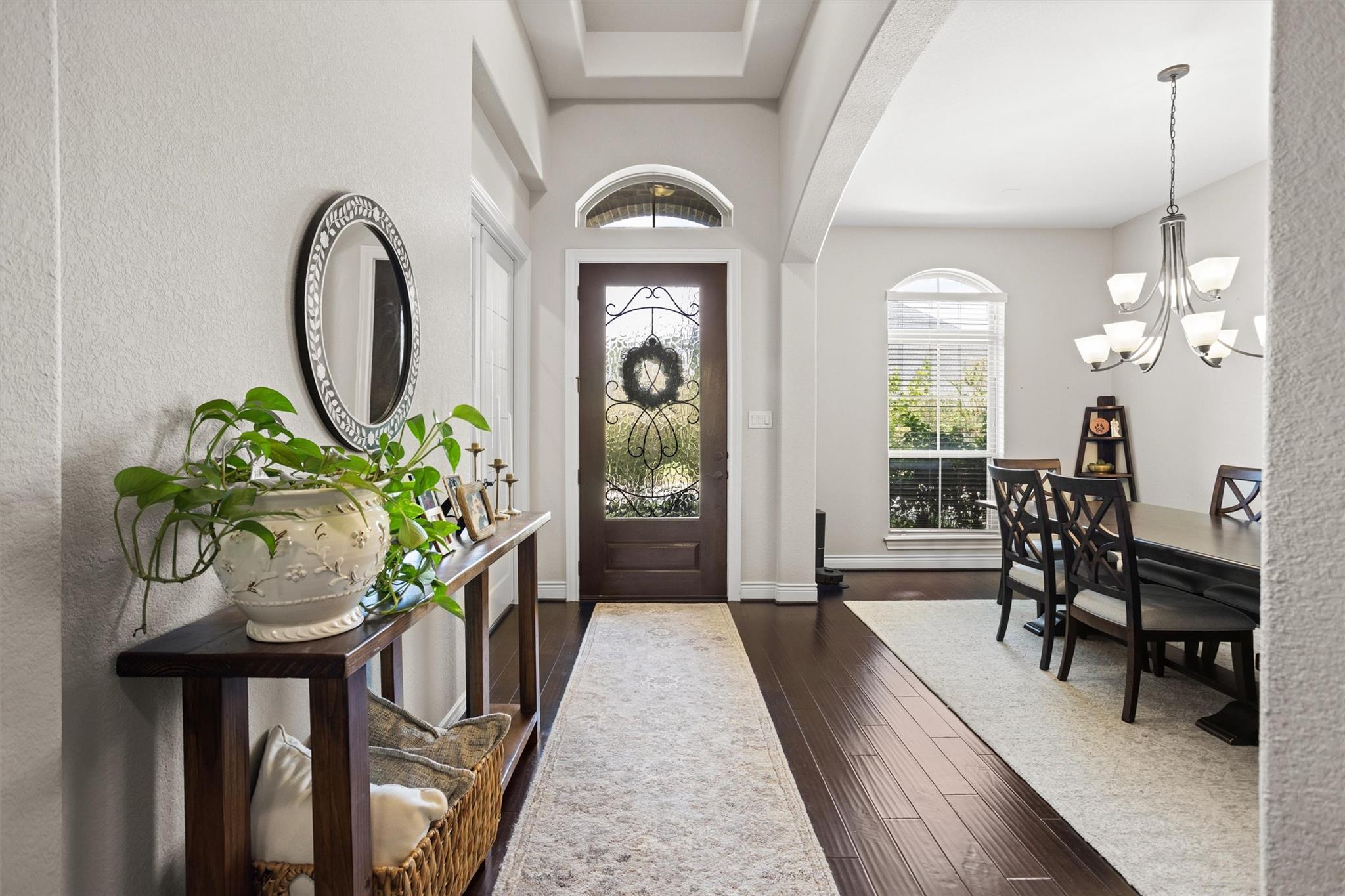 Home entryway with a decorative glass front door, console table, and adjoining dining area.