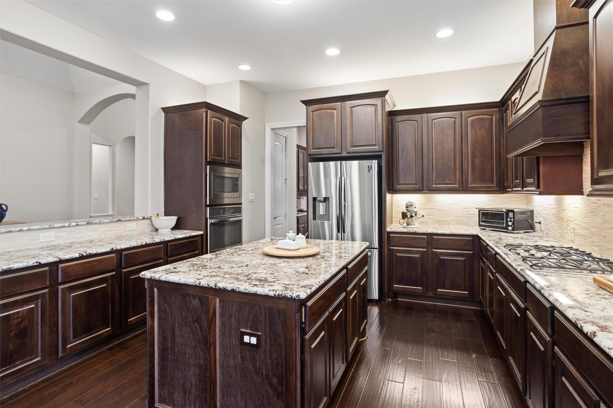 Kitchen with dark wood cabinets, granite counters, a central island, and stainless steel appliances.