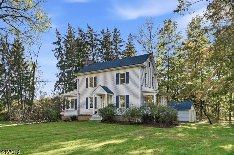 Two-story white house with dark shutters, a small attached garage, and a broad green lawn.