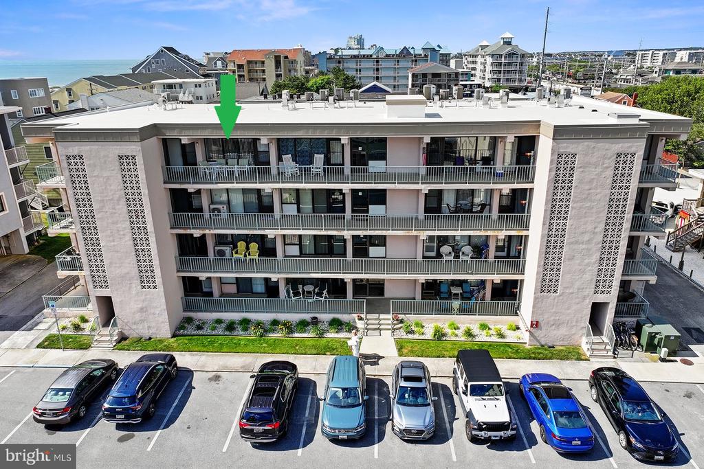 Aerial view of a condominium building, with a green arrow marking an upper-floor unit.