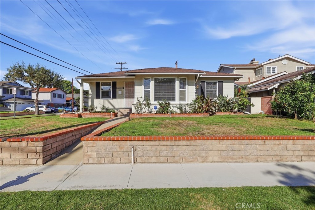 Single-story house with a raised front lawn, brick-capped retaining walls, and a walkway.