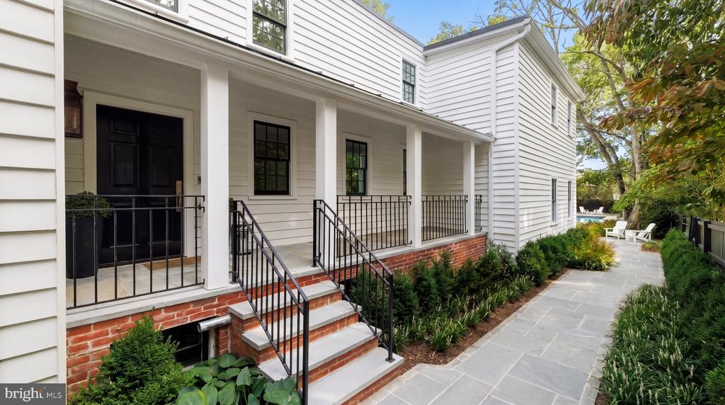White-sided home with a covered porch, brick steps, and a landscaped stone walkway.