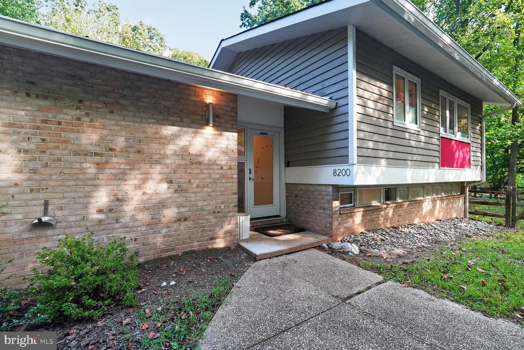Split-level home with brick and gray siding, a covered entry, and a concrete walkway.